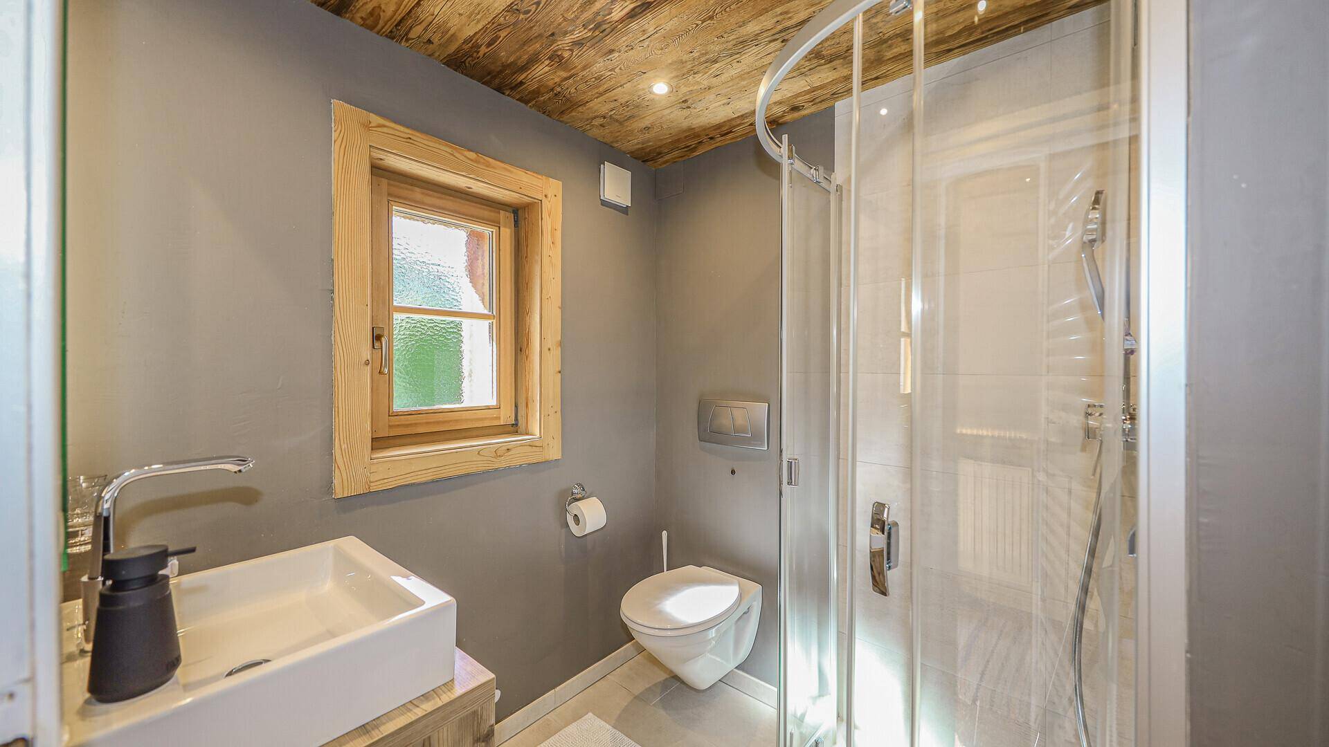 Modernes Badezimmer mit Dusche, Waschbecken und Holzdecke.