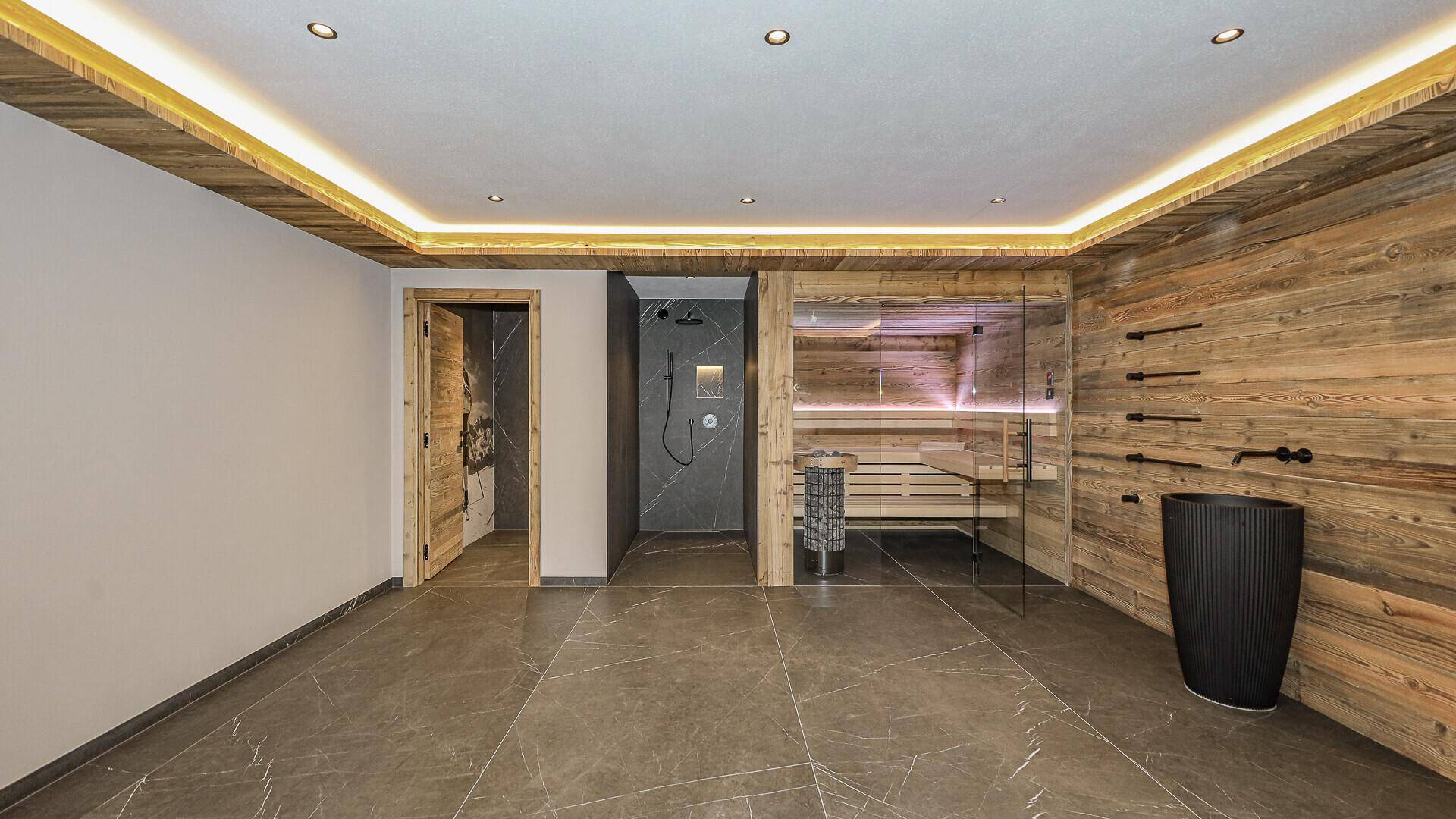 Luxuriöser Wellnessbereich mit Glas-Sauna, Regendusche und großformatigen Fliesen.