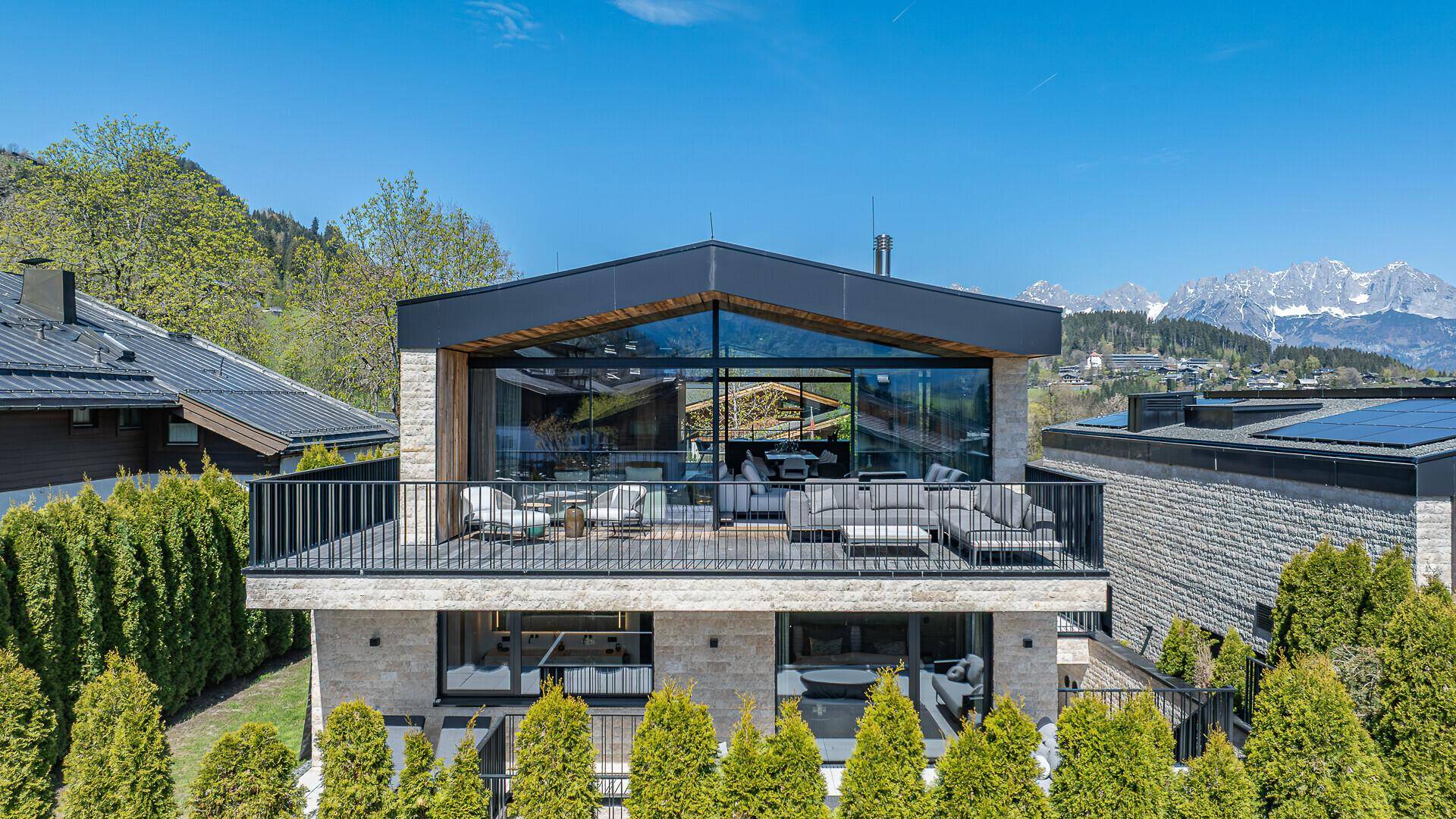 Moderne Villa mit großzügiger Terrasse, Glasfronten und beeindruckendem Bergblick in sonniger Lage.