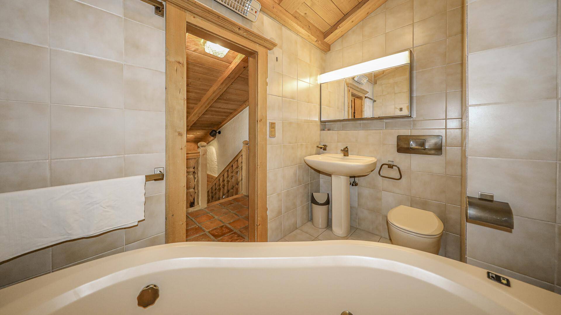 Funktionales Badezimmer mit Badewanne, Waschtisch und hellen beigefarbenen Fliesen.