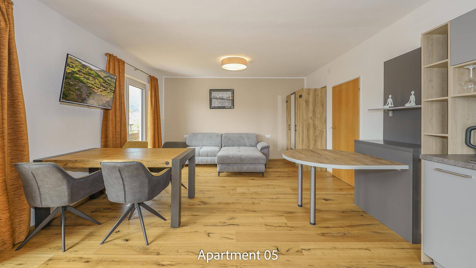 Geräumiger offener Wohnbereich von Apartment 05 mit bequemer Couch, Esstisch und moderner Einrichtung.