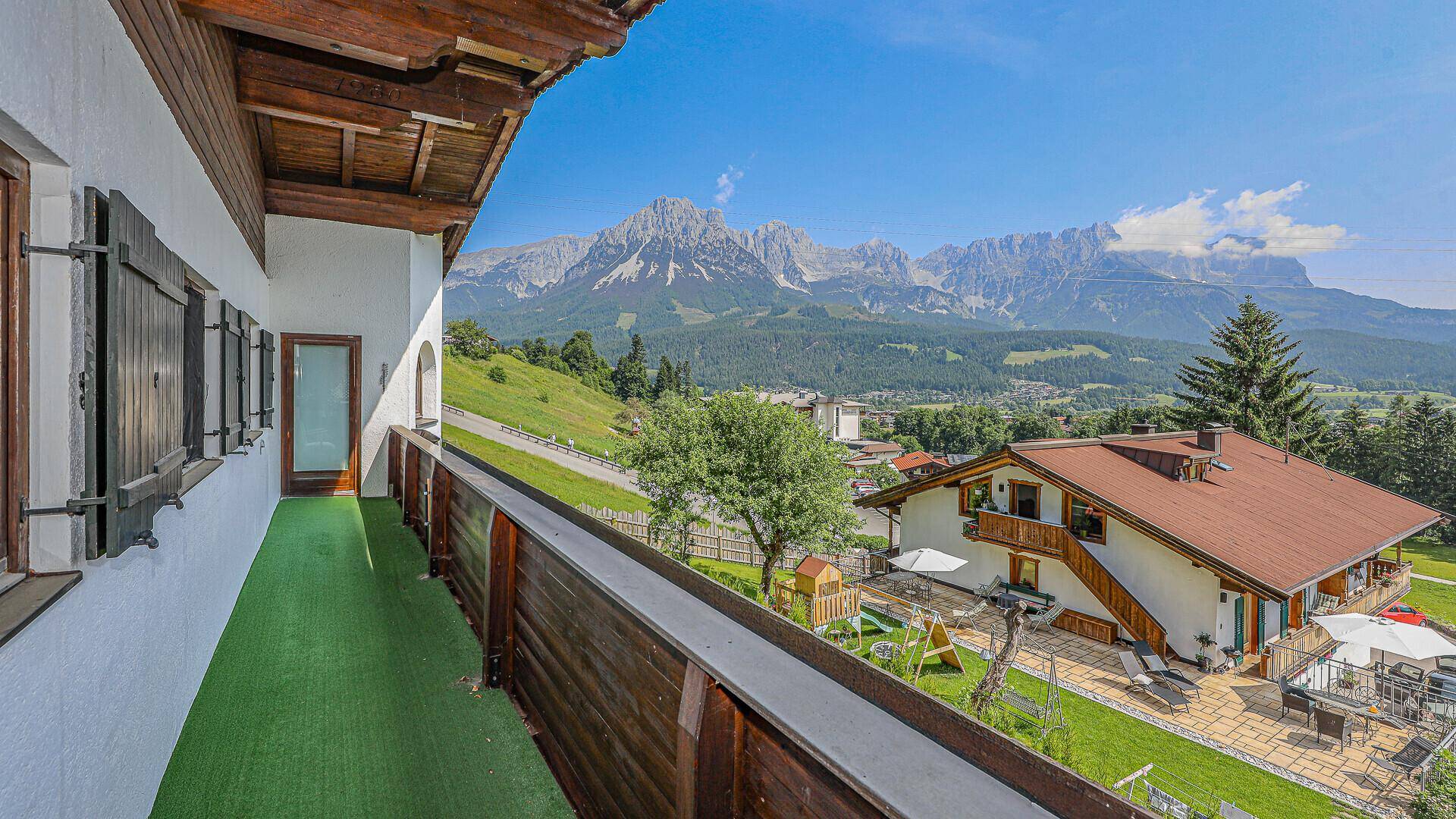 Langer Balkon mit Kunstrasen und weitem Blick auf die Berge und die umliegende Landschaft.