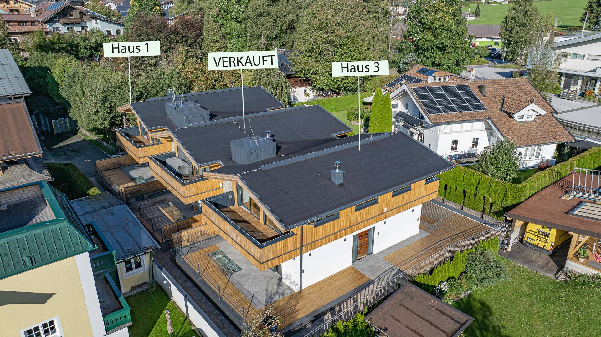 Luftaufnahme eines modernen Wohnkomplexes mit mehreren Einheiten und Solaranlagen auf den Dächern.