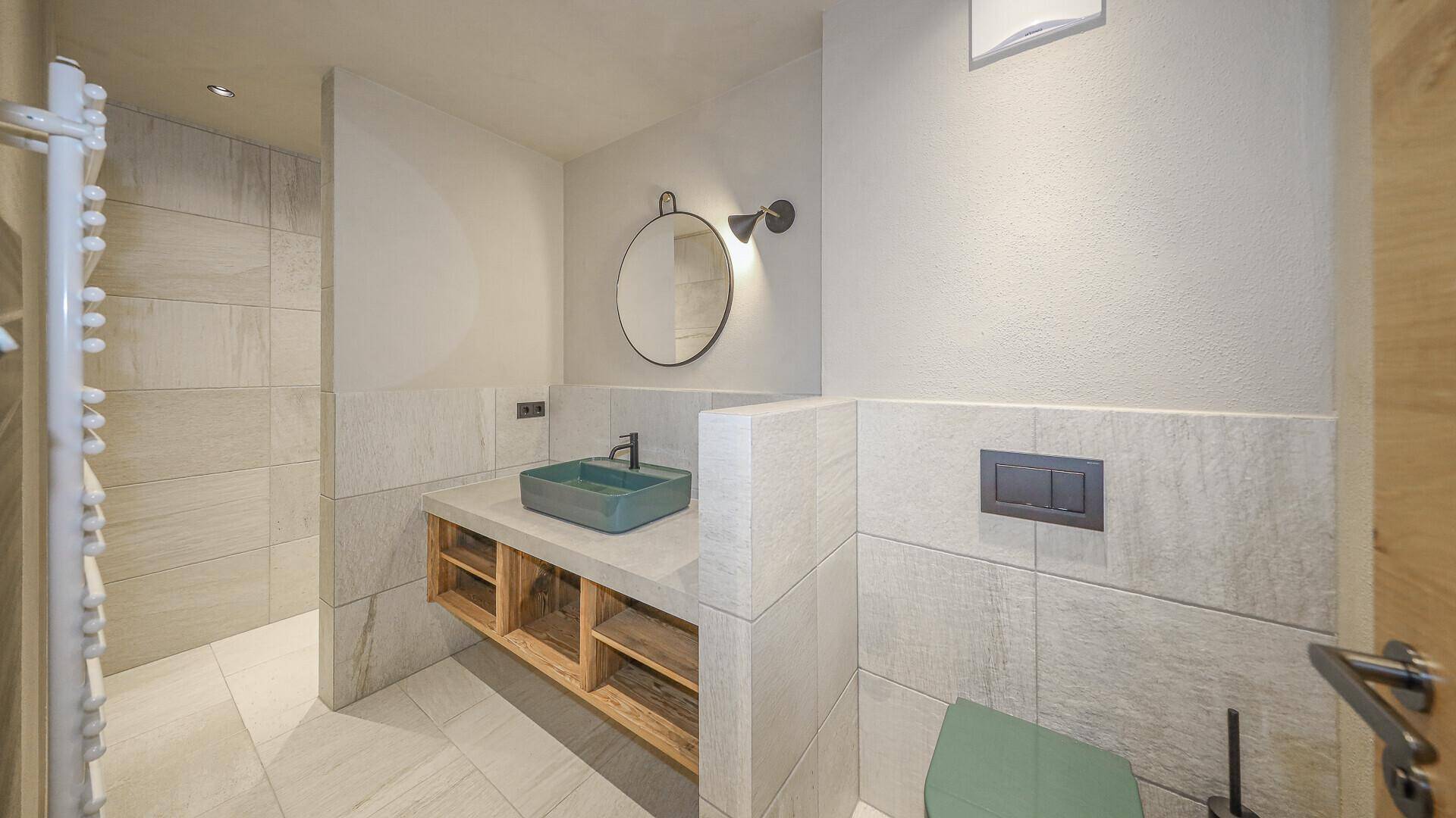 Modernes Gäste-WC mit Waschbecken, Wand-WC und hellen Fliesen an den Wänden.