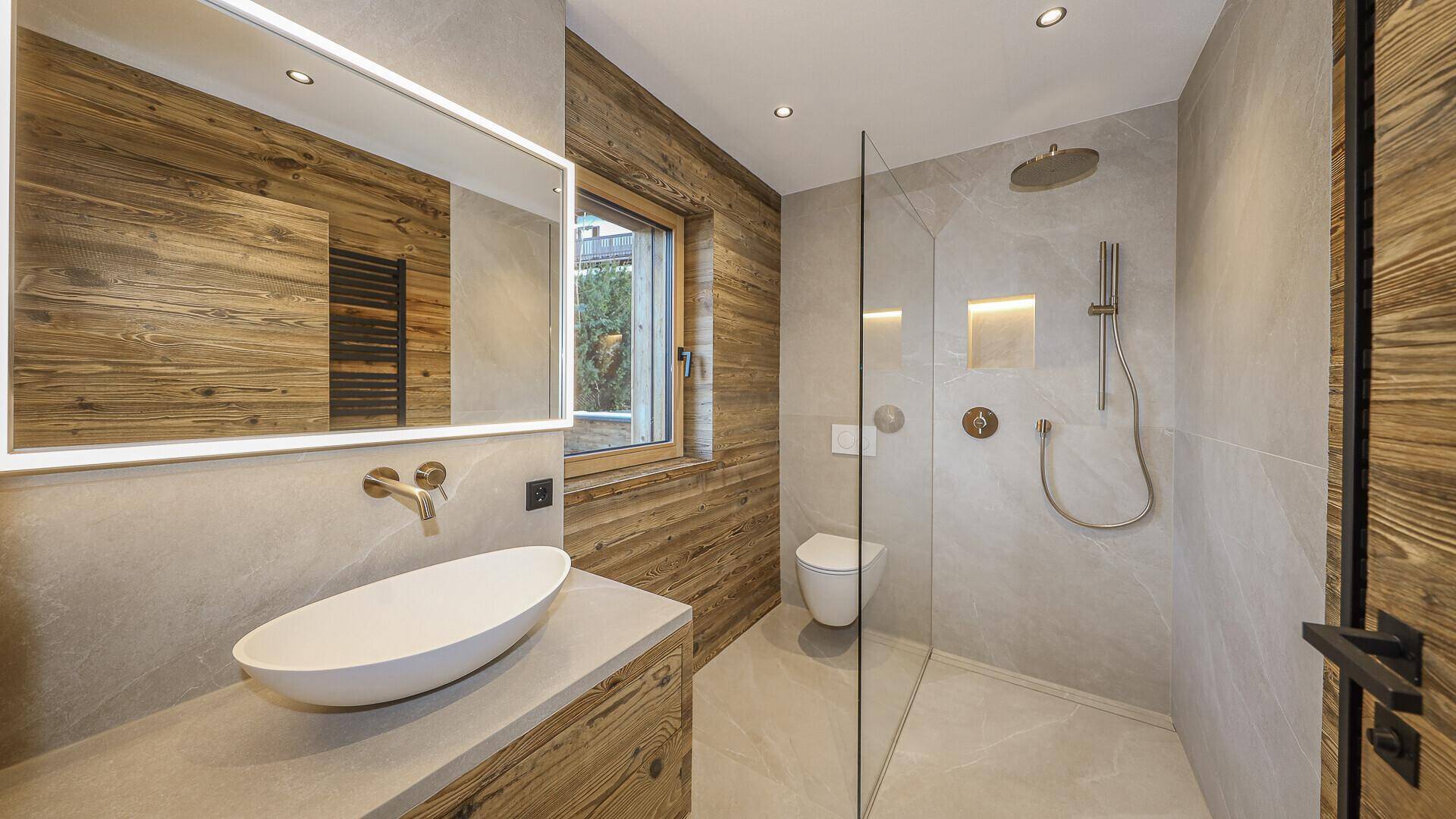Modernes Badezimmer mit begehbarer Dusche, ovalem Waschbecken und Holzdetails.