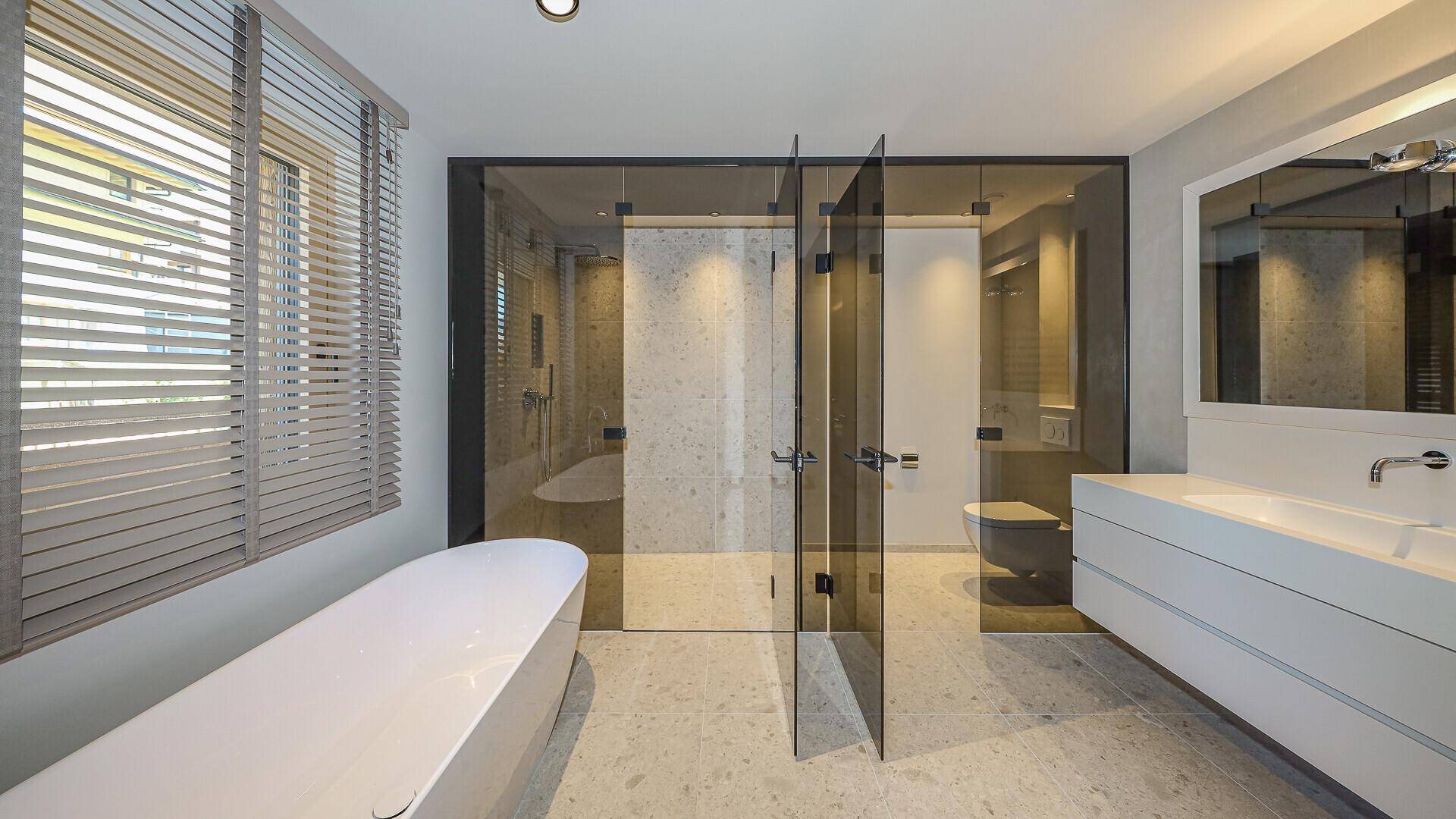 Luxuriöses Badezimmer mit freistehender Badewanne, großer Dusche und Doppelwaschbecken.