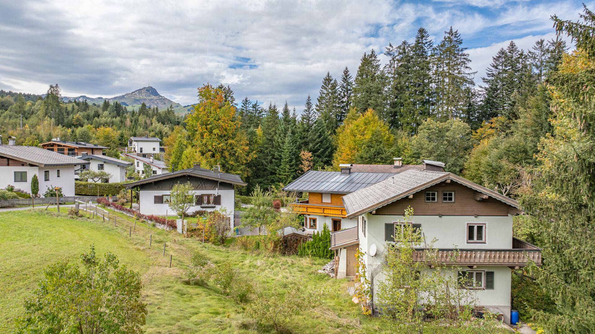 Detailansicht mehrerer Häuser in einer grünen Landschaft, einige mit Solaranlagen auf den Dächern.