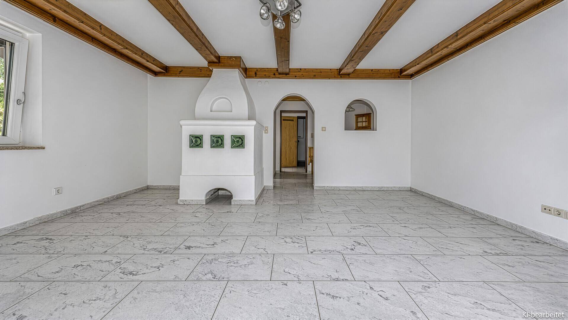 Leerer Raum mit Fliesenboden, Holzbalken und einem traditionellen Kachelofen, bereit zur Gestaltung.