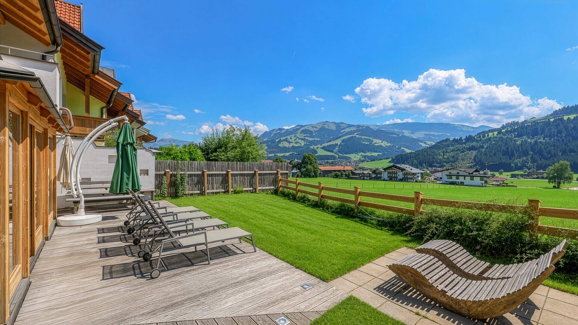 Sonnenterrasse mit Holzliegestühlen und direktem Zugang zum Garten mit Bergblick.