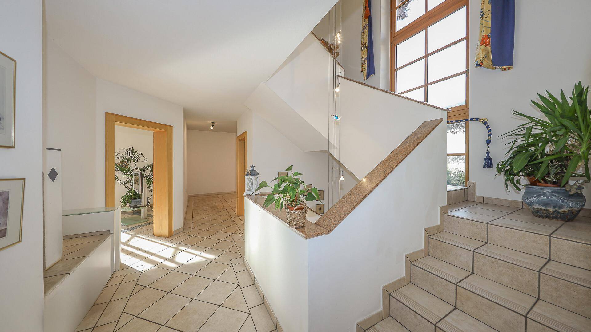 Geräumiger Eingangsbereich mit gefliestem Boden, Treppe und natürlichem Lichteinfall.