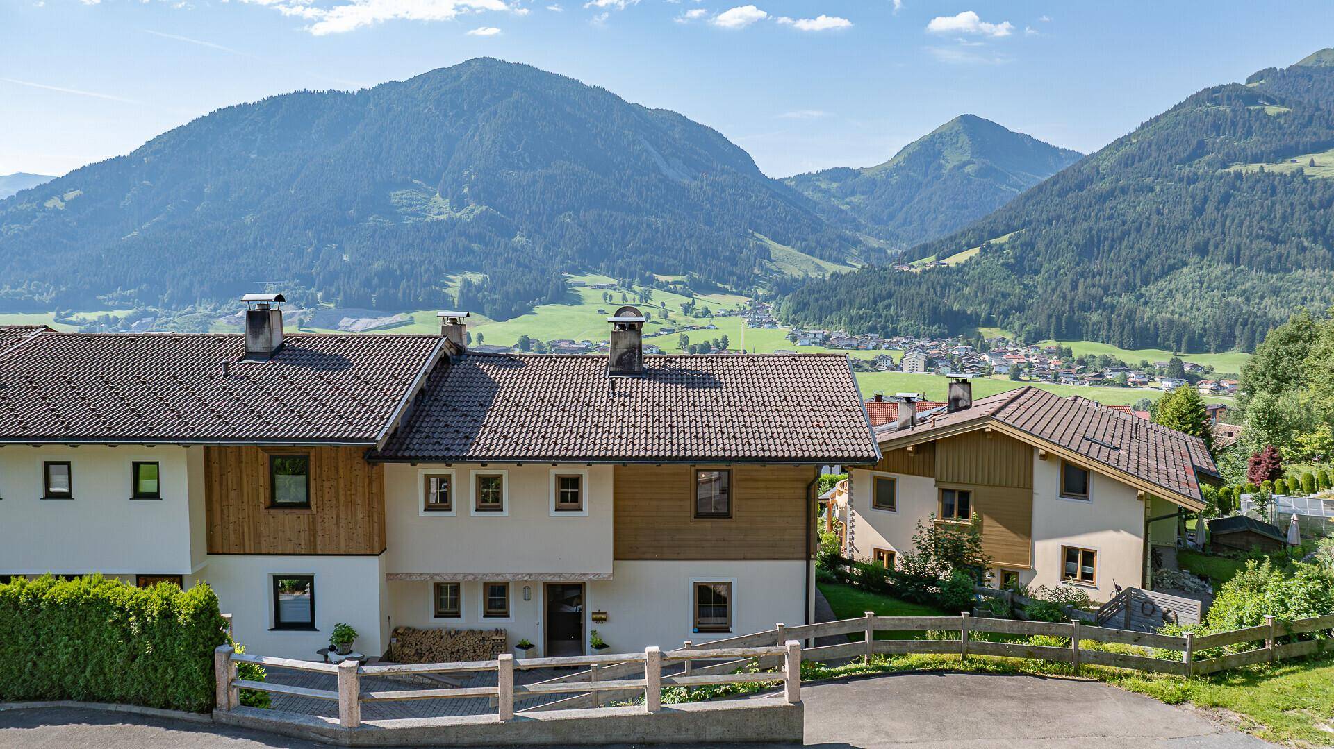 Traditionelle Häuser in alpiner Umgebung mit weitem Blick auf die Berge und das Tal.