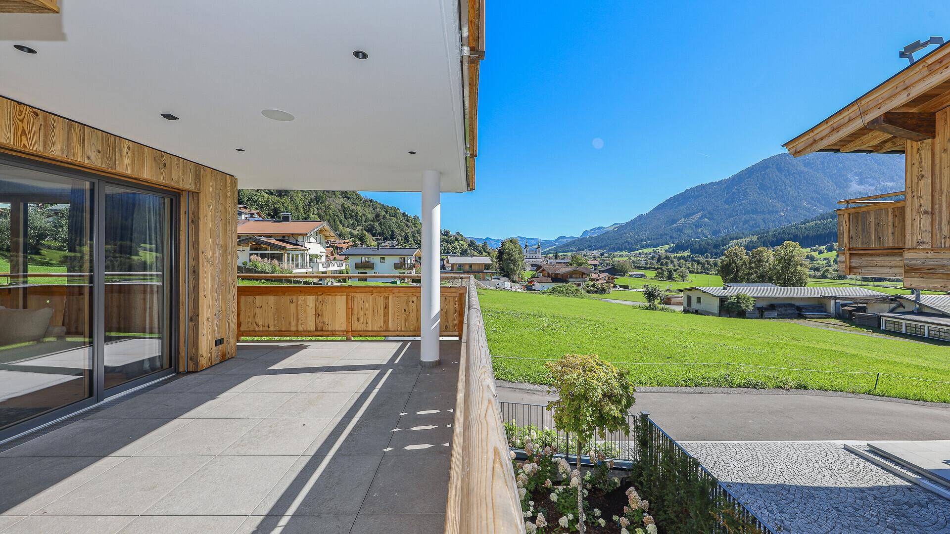 Große, sonnige Terrasse mit Fliesenboden und weitem Blick auf die grüne Berglandschaft.