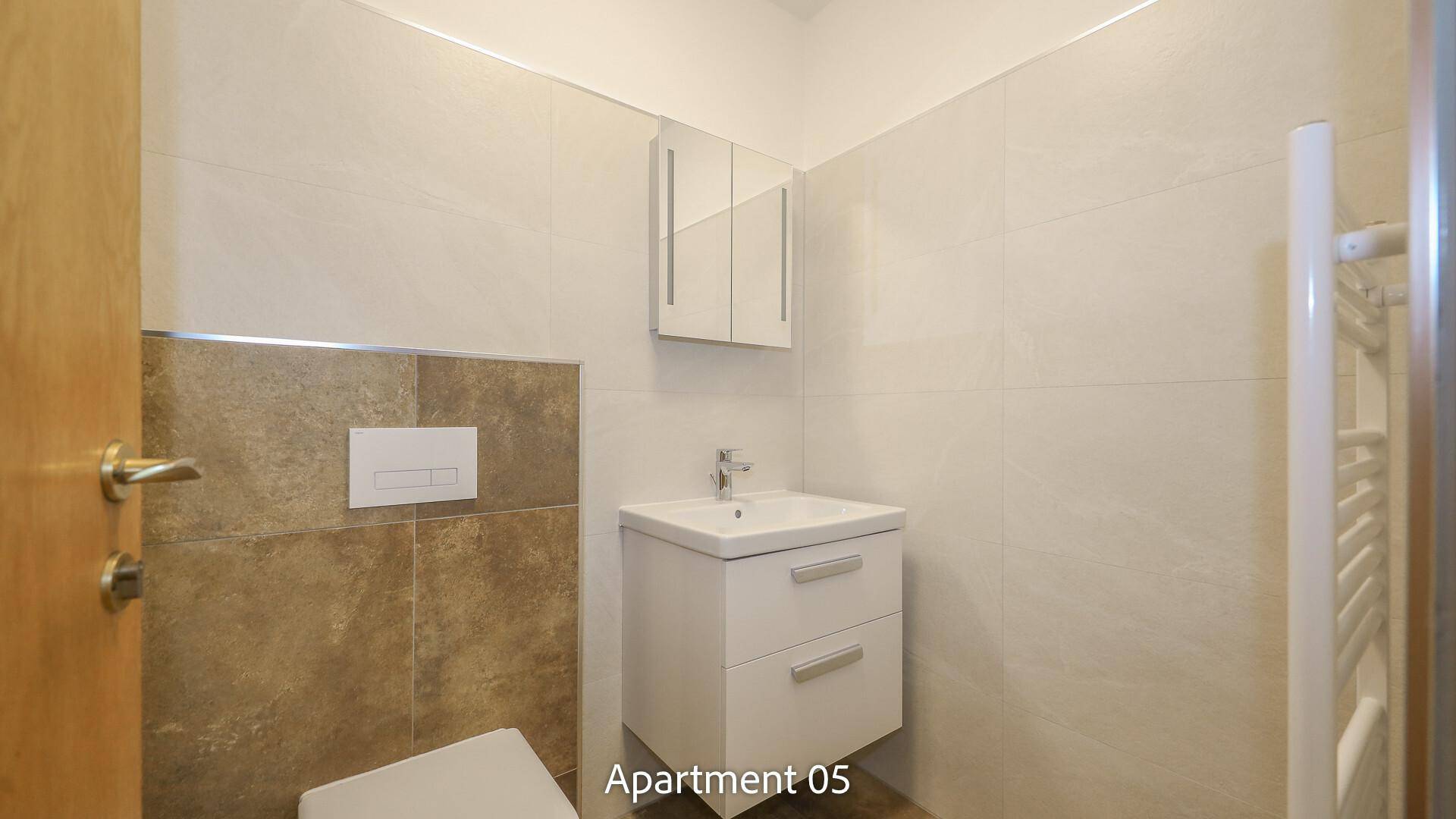 Modernes Badezimmer von Apartment 05 mit hellen Fliesen, Waschtisch und wandhängendem WC.