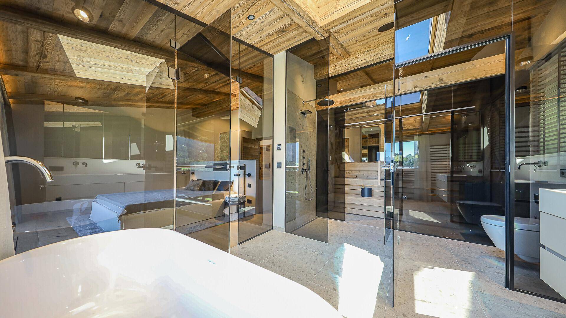 Luxuriöses Badezimmer mit Glaswänden, freistehender Badewanne, Dusche und Sauna.