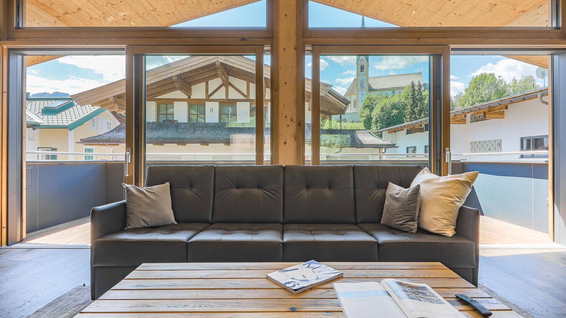 Wohnzimmer mit großem Sofa und bodentiefen Fenstern, die einen Blick auf die Nachbarschaft bieten.