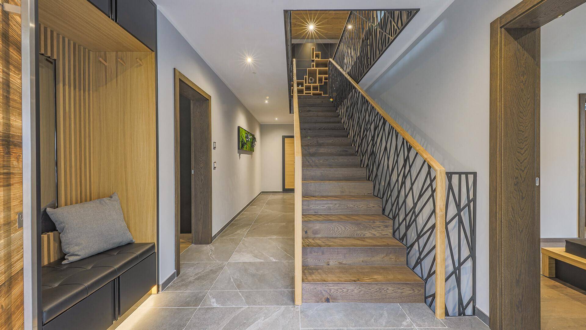 Geräumiger Flur mit Holztreppe, Sitzbank und modernem Design, führt zu den oberen Etagen.