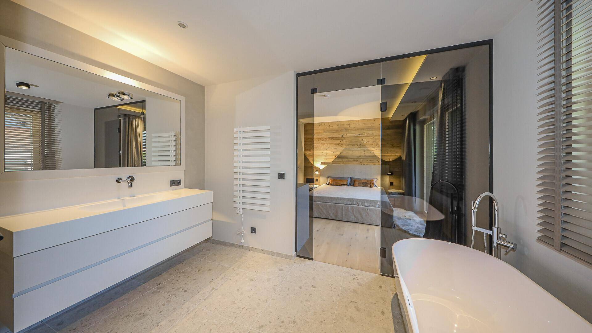 Elegantes Badezimmer mit freistehender Badewanne und Blick in das angrenzende Schlafzimmer.