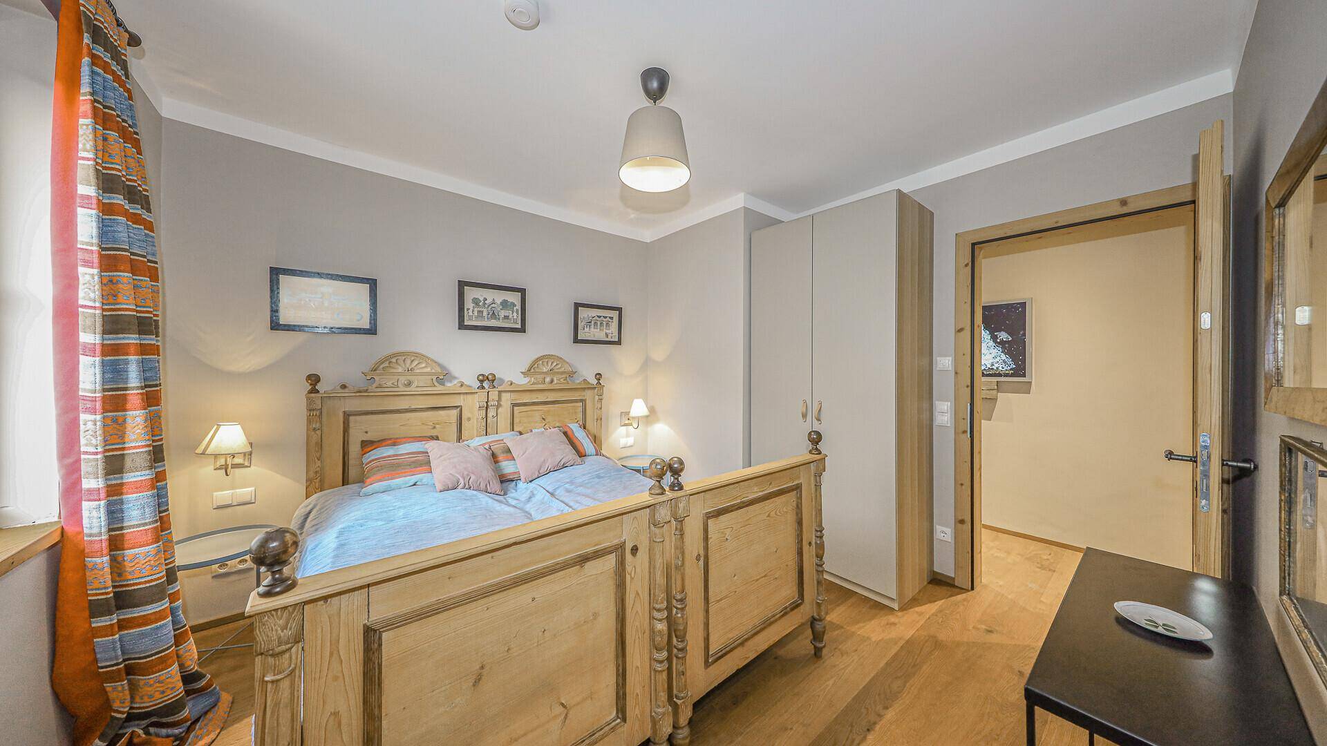 Helles Schlafzimmer mit traditionellem Holzbett und Einbauschrank im alpinen Stil.