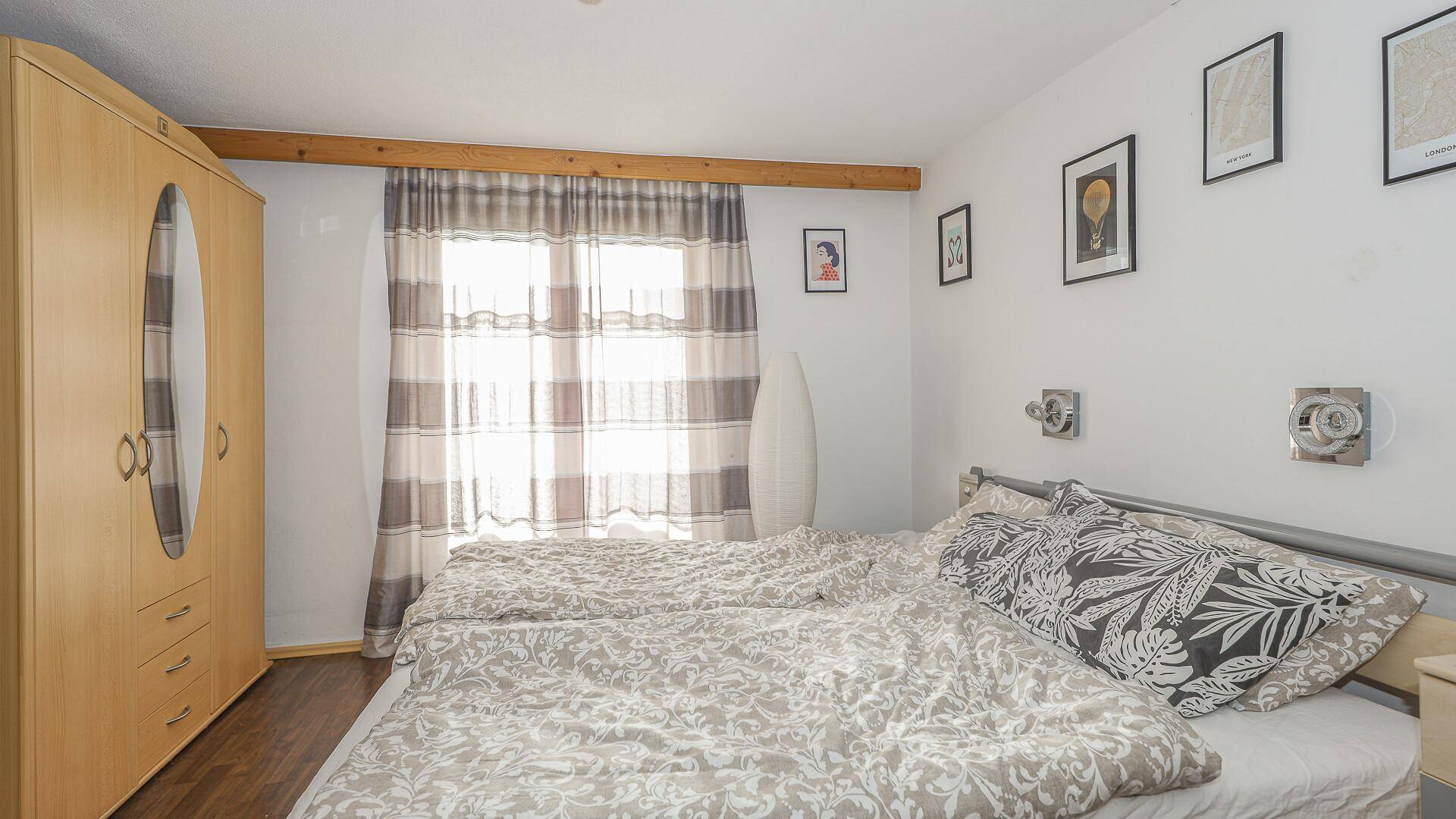 Schlafzimmer mit Doppelbett, Kleiderschrank und Fenster mit Blick nach draußen.