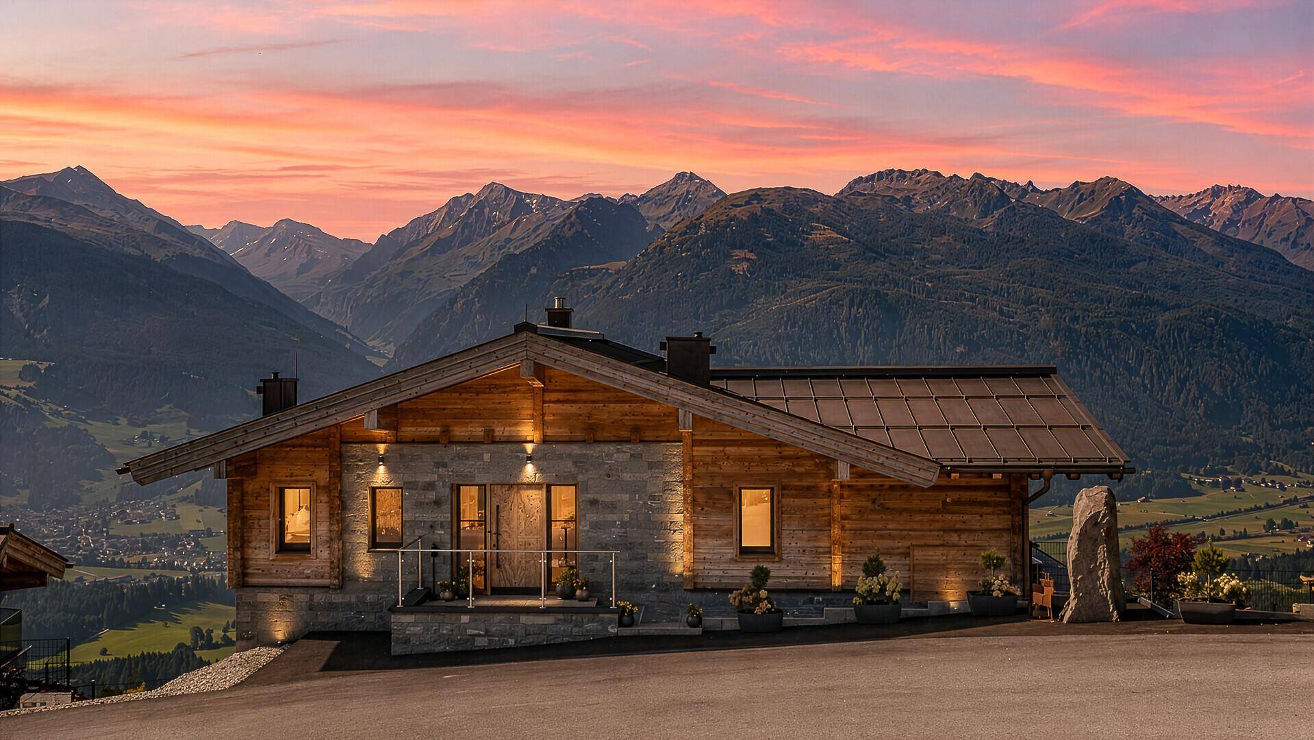 Alpines Chalet bei Sonnenuntergang mit beeindruckendem Bergblick und warmer Beleuchtung.