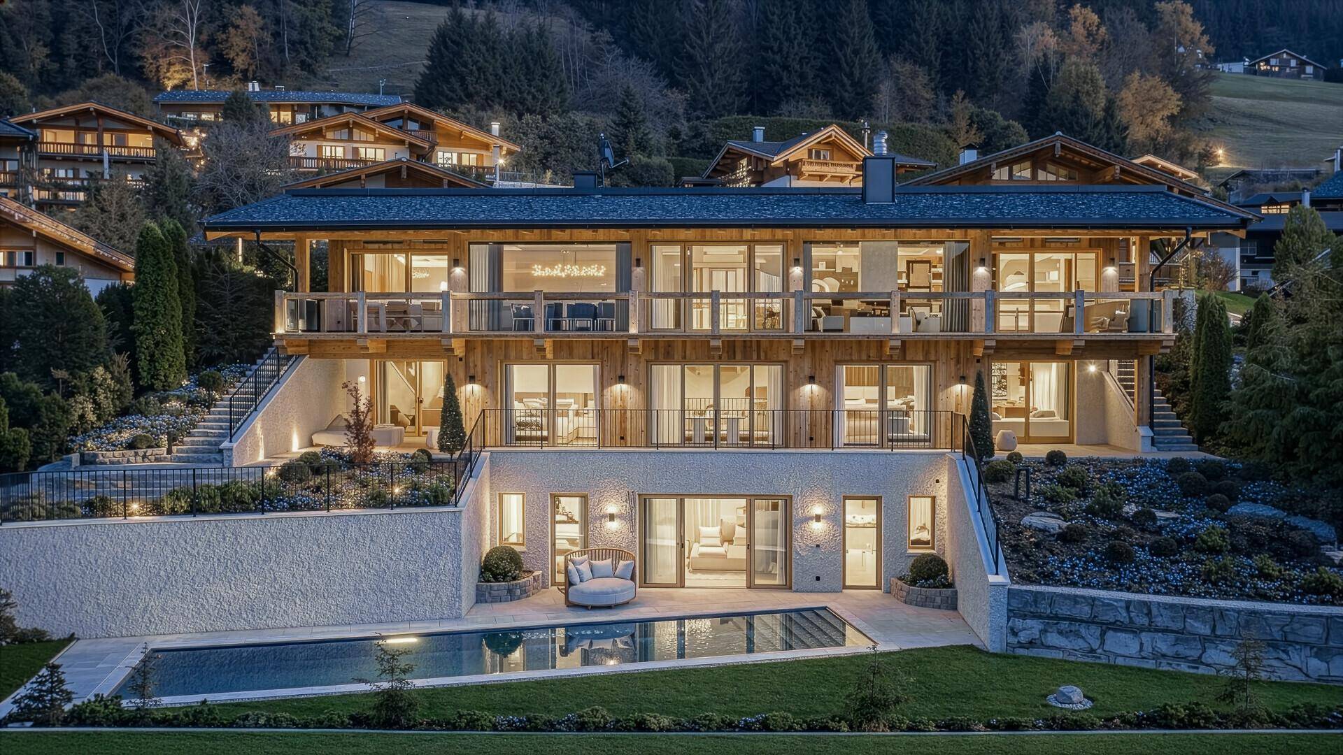 Beleuchtetes Luxusanwesen bei Nacht mit Pool, Garten und stimmungsvoller Außenbeleuchtung.