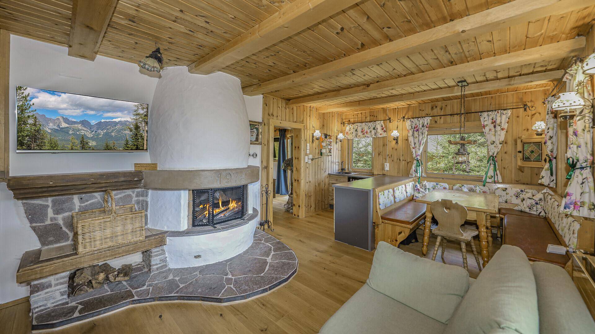 Rustikaler Wohnbereich mit Kachelofen, Holzbalkendecke und Essbereich im Landhausstil.