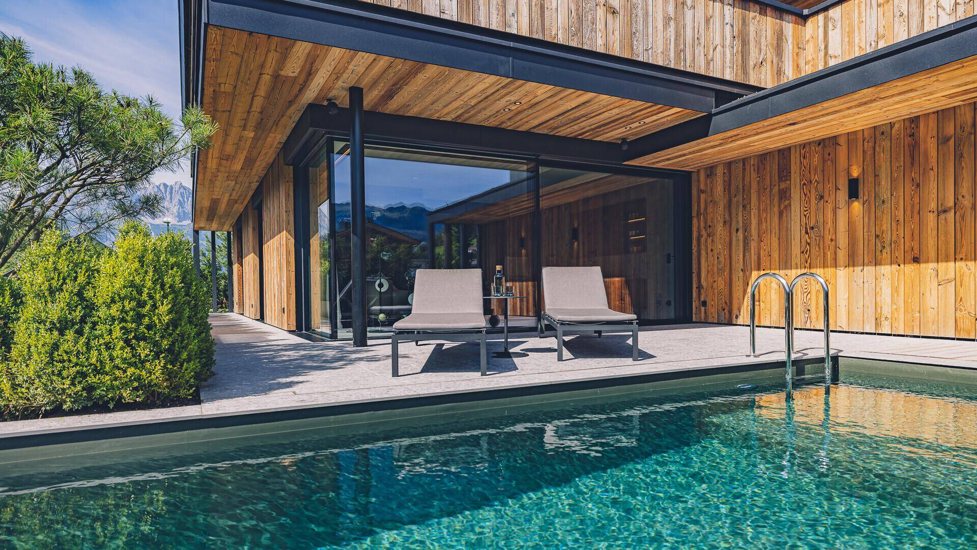 Außenpoolbereich mit Sonnenliegen und direktem Zugang zum modernen Wohnhaus.