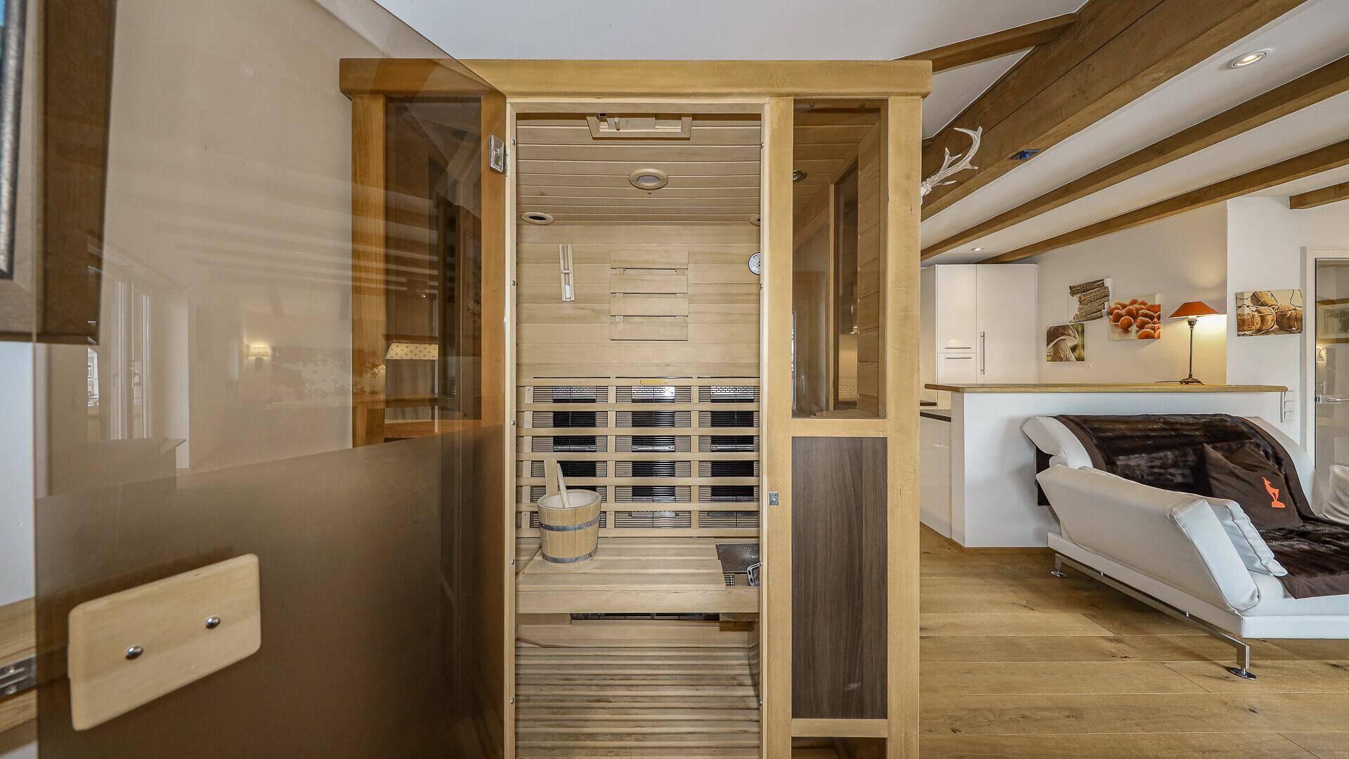 Private Sauna mit Holzbänken und traditionellem Aufgusseimer, offen zum Wohnbereich.
