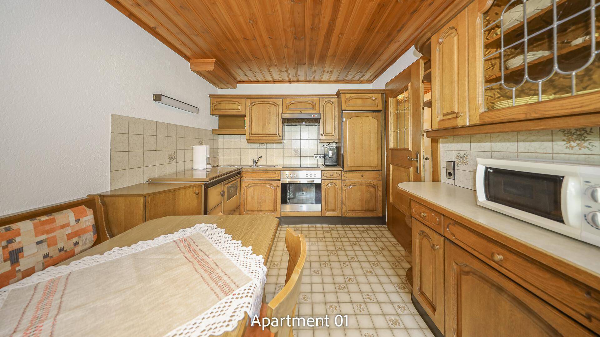 Traditionelle Küche von Apartment 01 mit Holzschränken, Fliesenboden und integrierten Geräten.