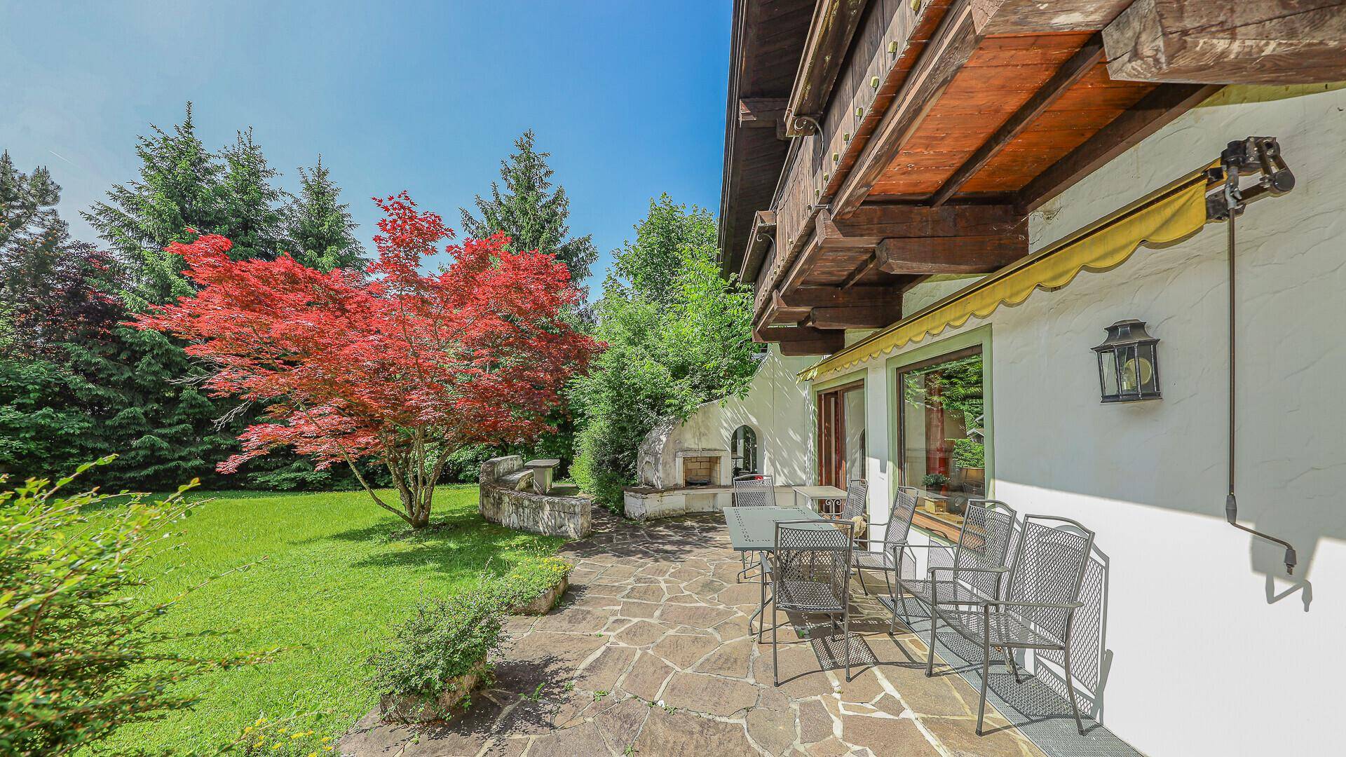 Gemütliche Steinterrasse mit Gartenmöbeln und Blick auf den gepflegten Garten und die Natur.