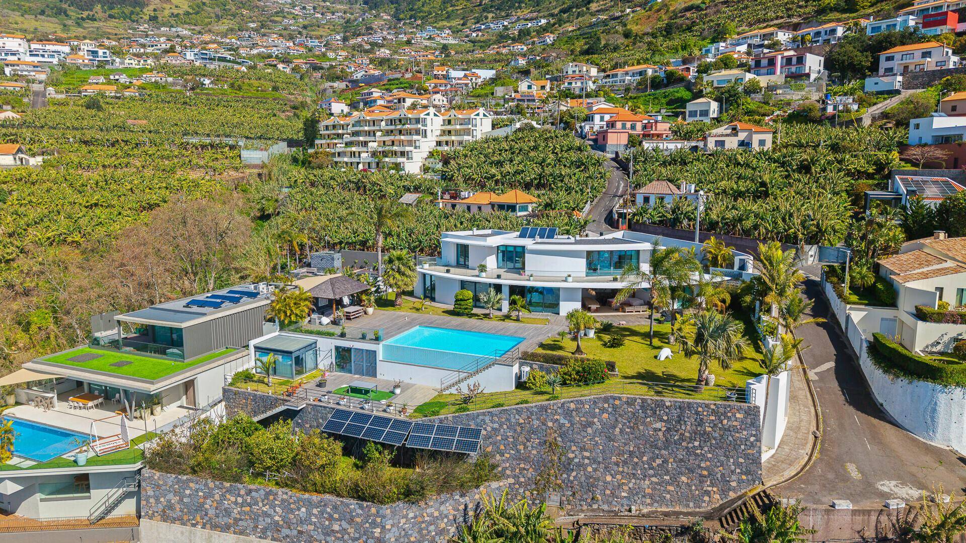 Exklusive Villa am Hang mit Infinity-Pool, umgeben von üppiger Vegetation und Bananenplantagen.