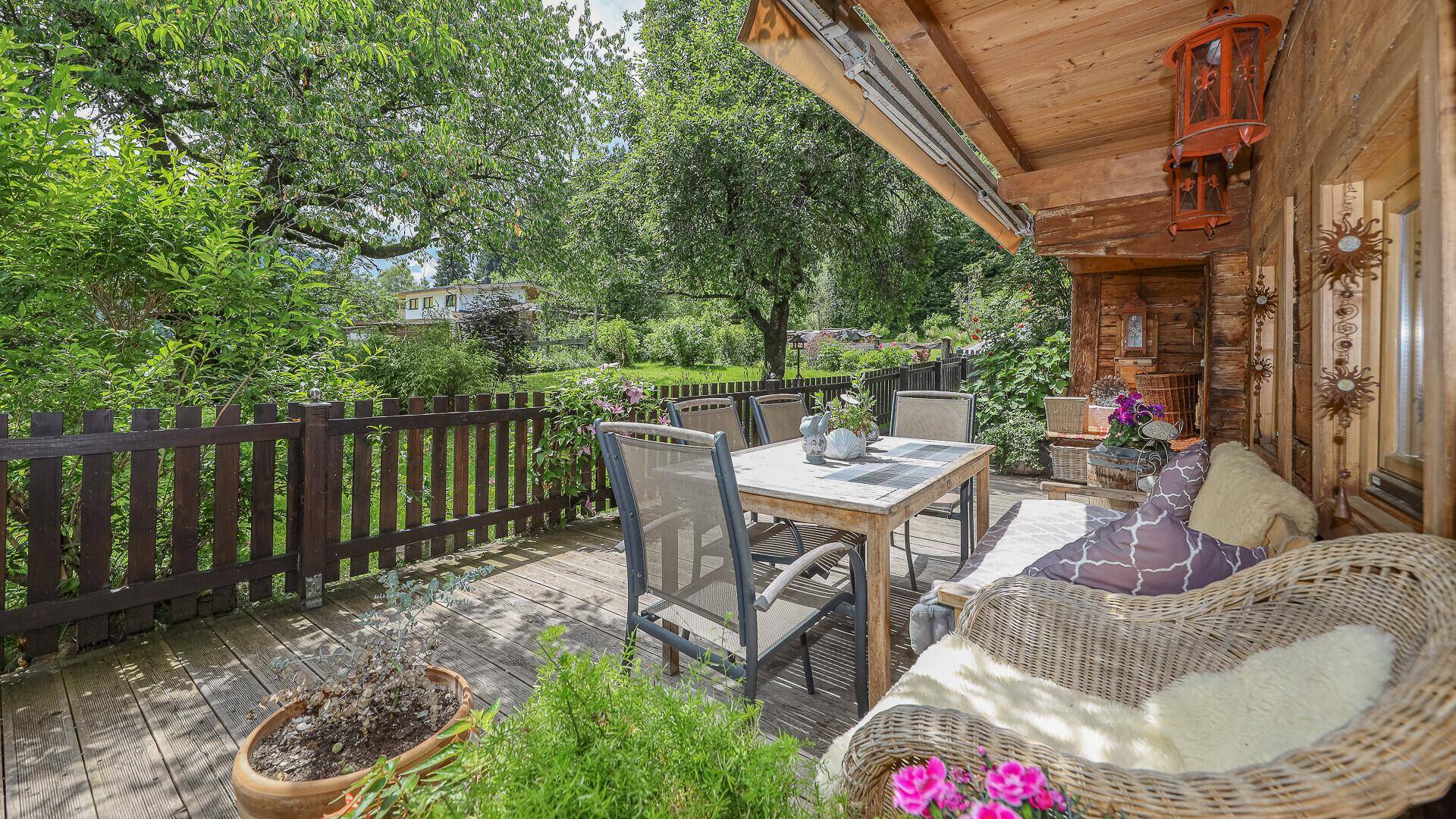 Gemütliche Holzterrasse mit Sitzgelegenheiten und Blick auf den weitläufigen Garten.