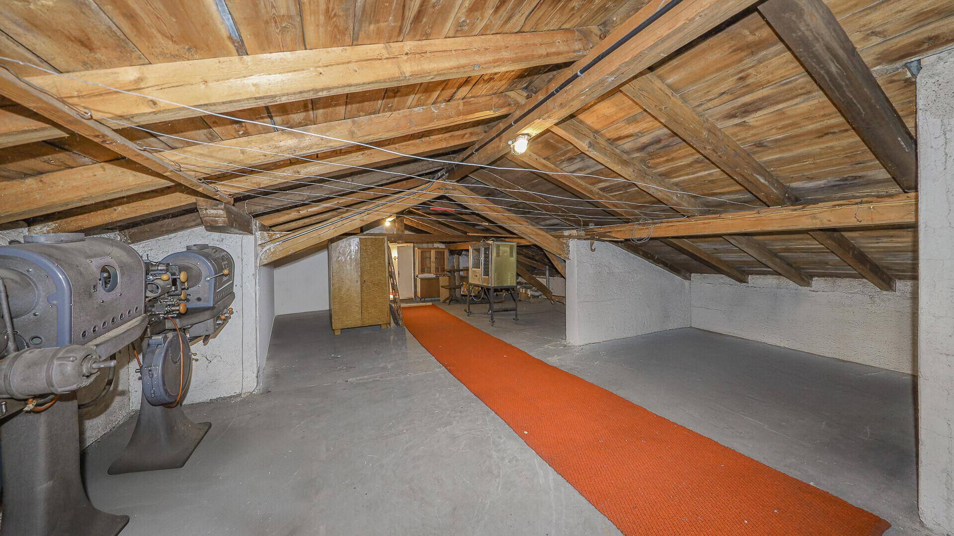 Geräumiger Dachboden mit sichtbaren Holzbalken, Betonboden und viel Stauraum.