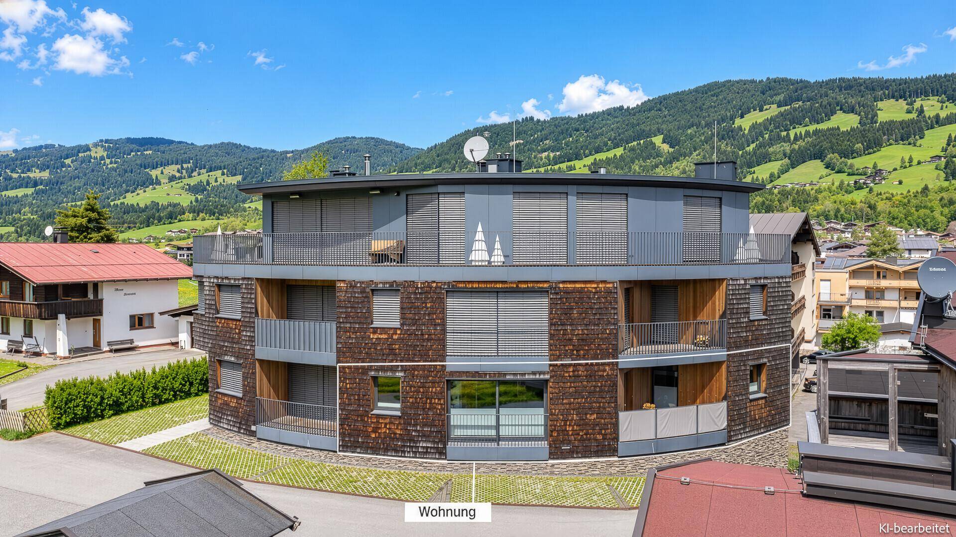 Moderne Wohnanlage mit runder Architektur und Holzfassade in den Bergen.