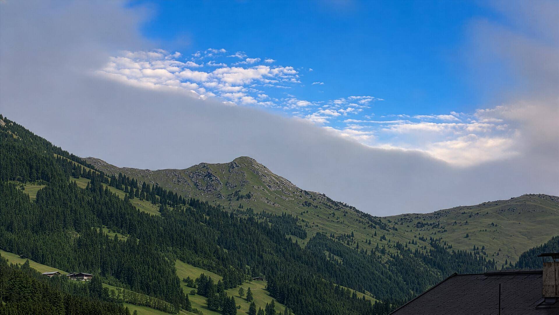 Weitläufige Berglandschaft mit grünen Hängen und bewölktem Himmel.