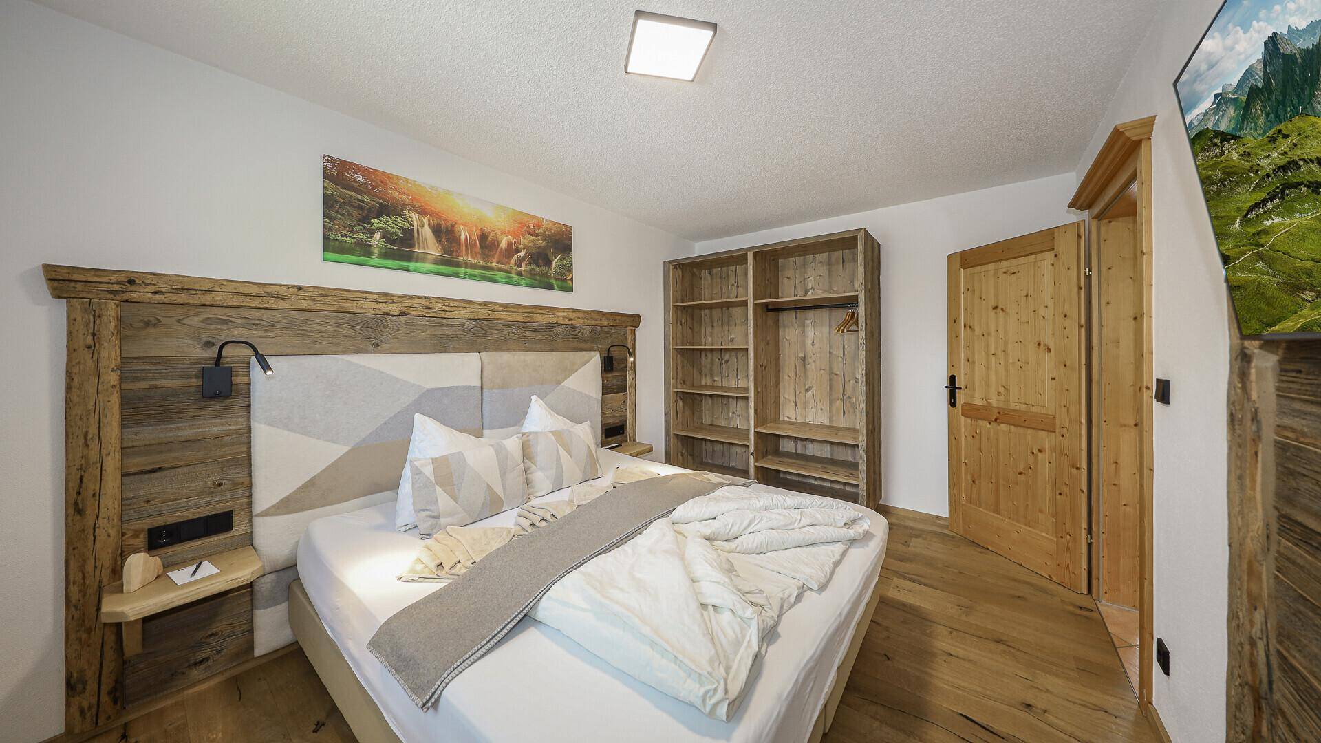 Schlafzimmer mit Doppelbett, Holzelementen und offenen Regalen für persönlichen Stauraum.
