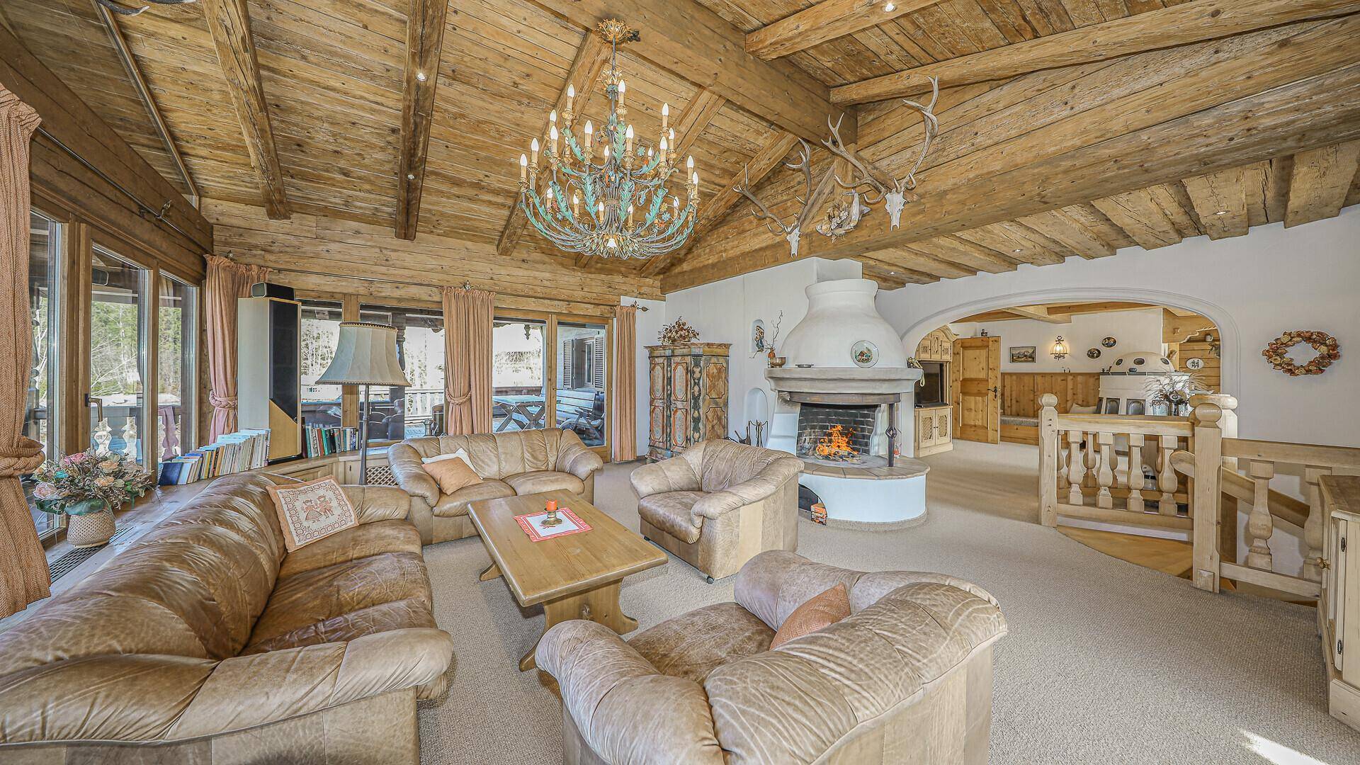 Geräumiges Wohnzimmer mit Kamin, Ledermöbeln und Holzbalkendecke im traditionellen Alpenstil.