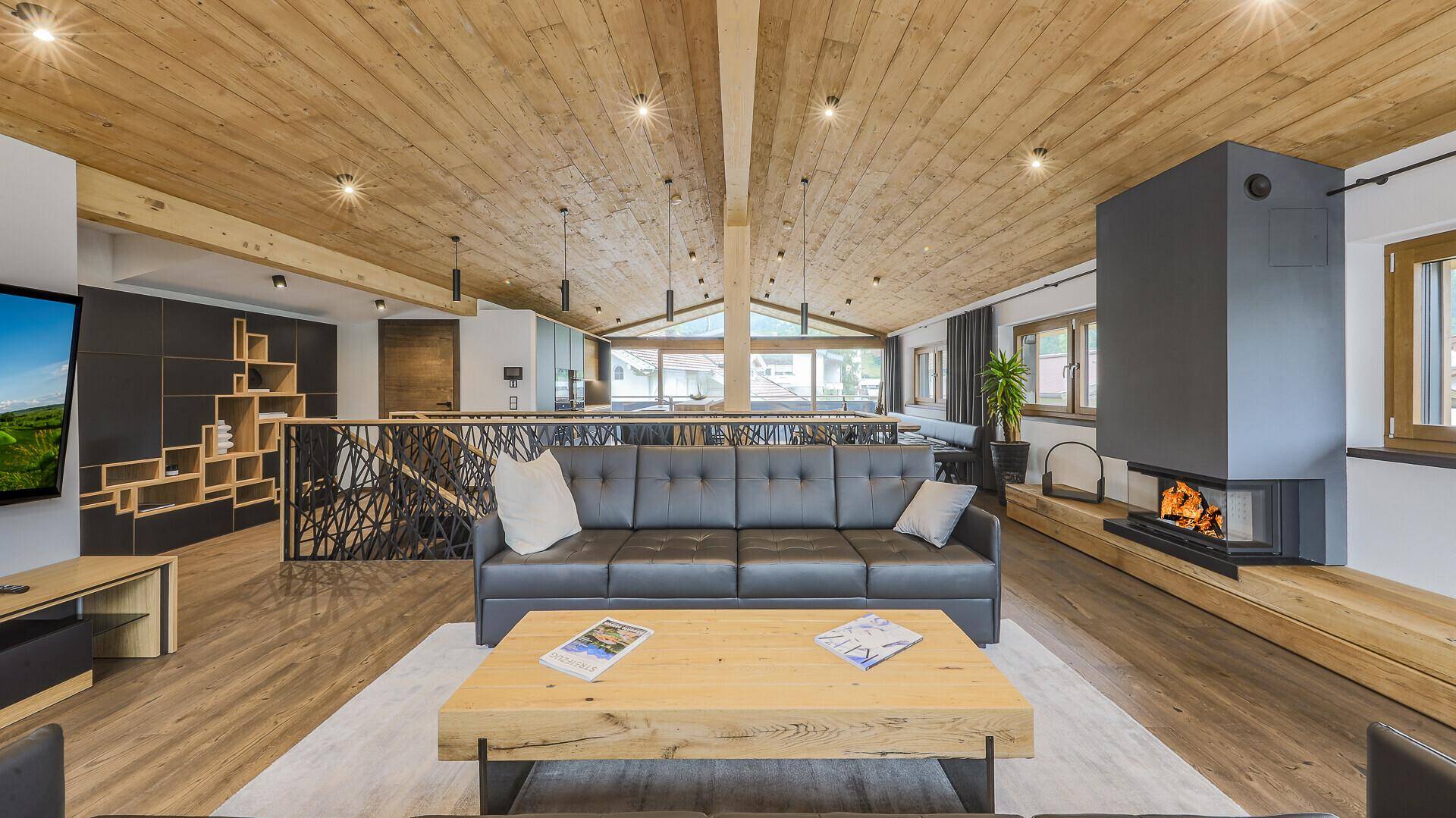 Heller Wohnbereich mit Kamin, Holzbalkendecke und bequemen Ledersofas in modernem Design.