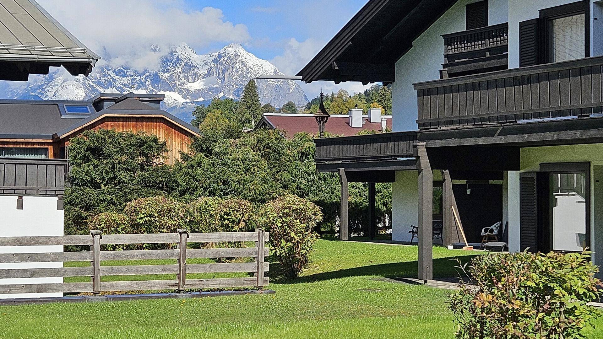 Gepflegter Gartenbereich mit Rasen und Blick auf die schneebedeckten Berge.
