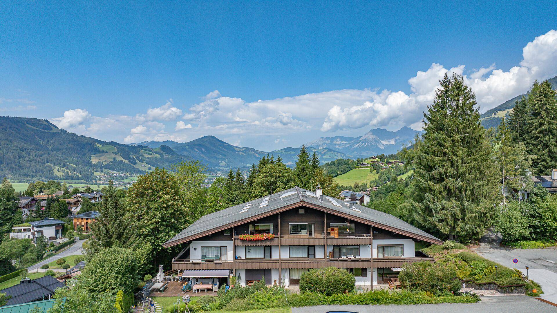 Charmantes Chalet mit mehreren Balkonen und herrlichem Bergblick in grüner Umgebung.