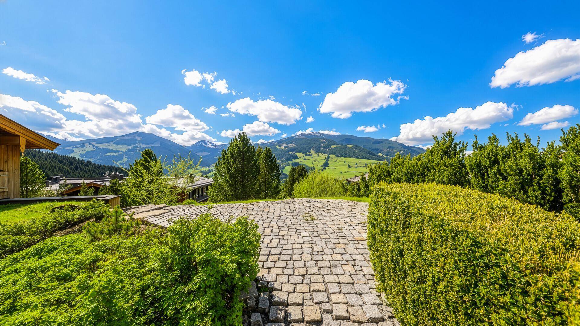 Malerischer Blick auf die umliegende Berglandschaft mit grünen Hügeln und blauem Himmel.