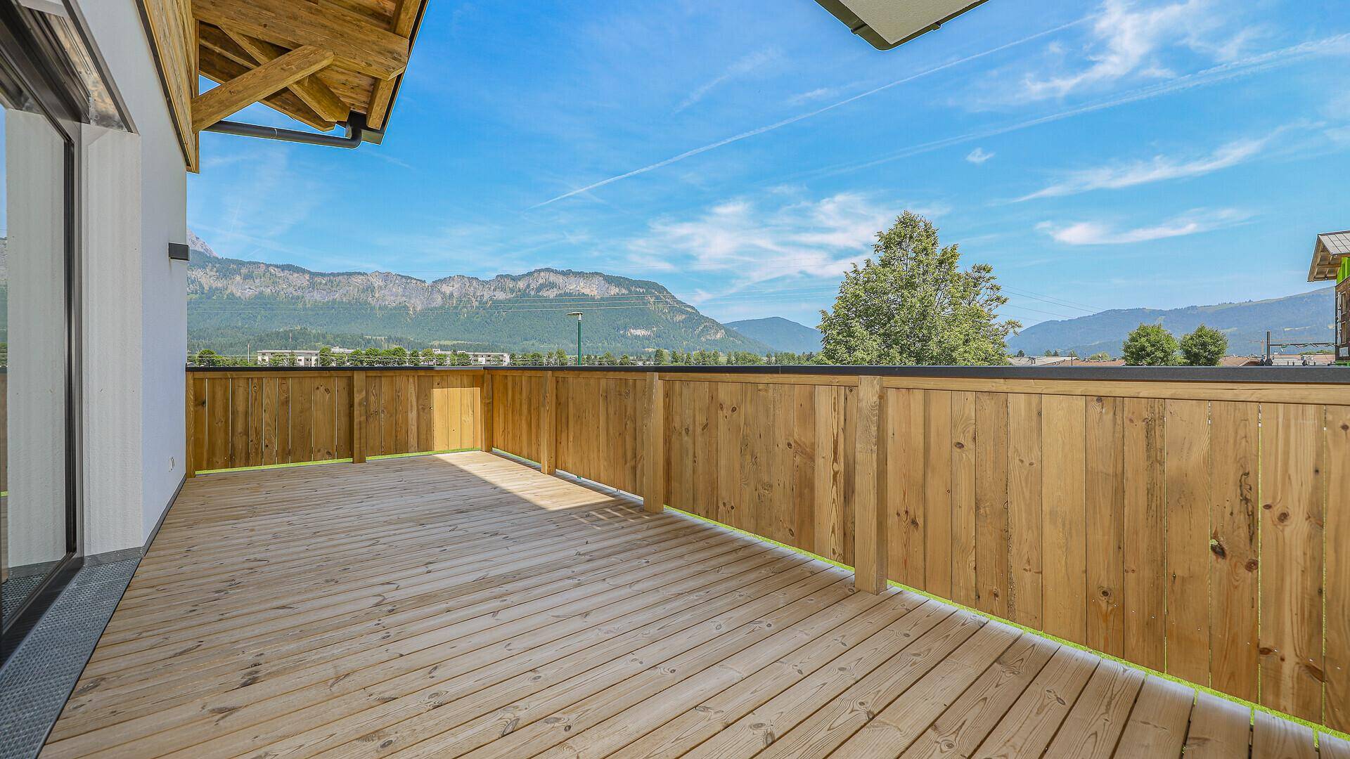 Breiter Balkon mit Holzboden und Holzgeländer, der einen weiten Blick in die Landschaft bietet.