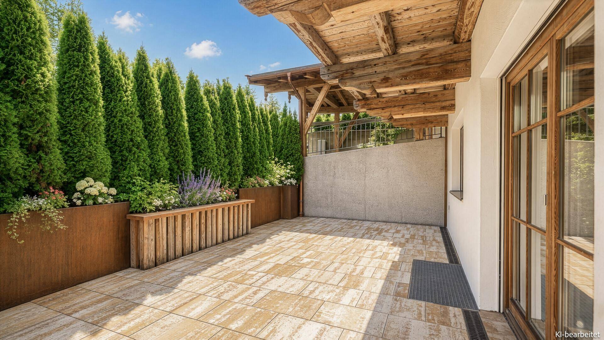 Geräumige Terrasse mit hohen Hecken und Holzelementen, bietet Privatsphäre und viel Platz.
