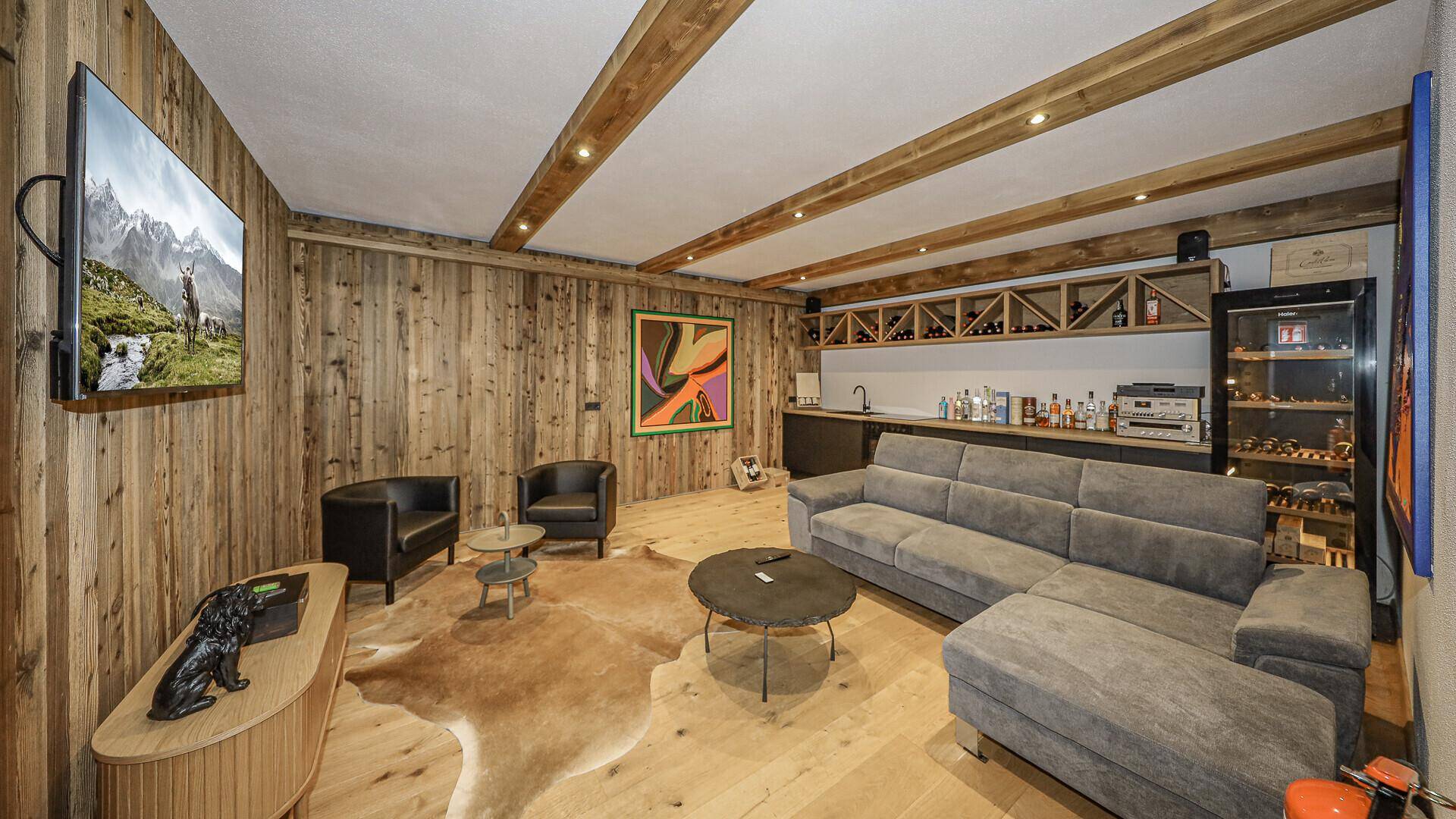 Gemütlicher Wohnbereich mit Holzwänden, Bar und Weinkühler für gesellige Abende.