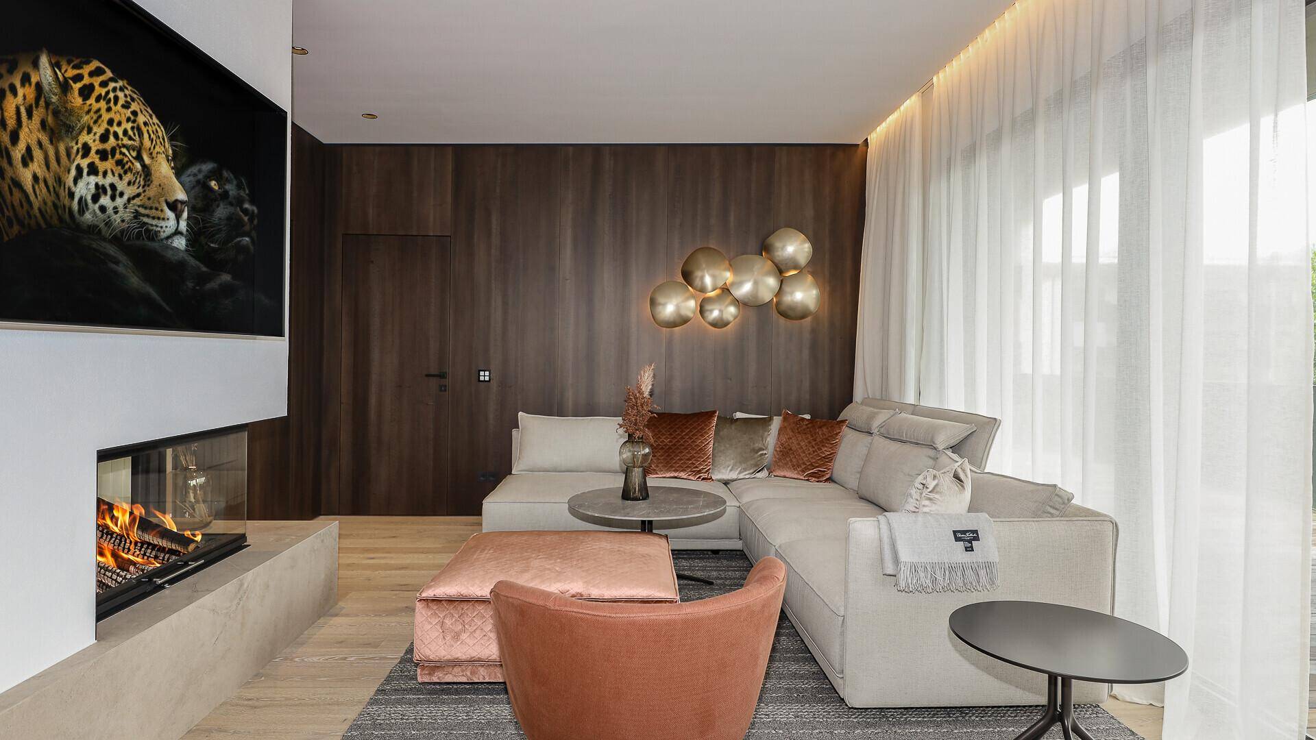 Gemütliches Wohnzimmer mit modernem Kamin, großem Sofa und Holzwänden für eine warme Atmosphäre.