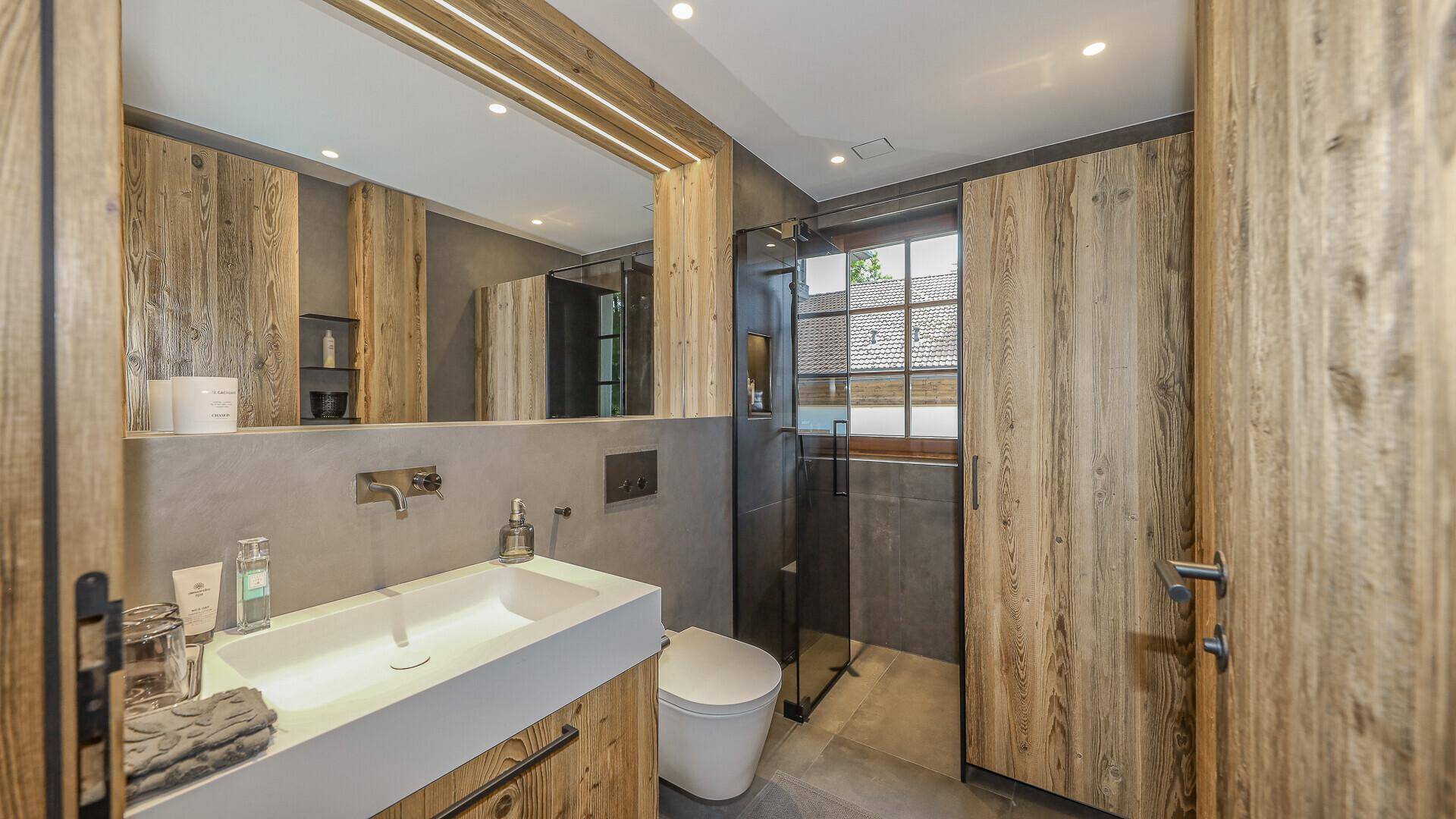 Stilvolles Badezimmer mit modernem Waschtisch, begehbarer Dusche und Holzvertäfelung.