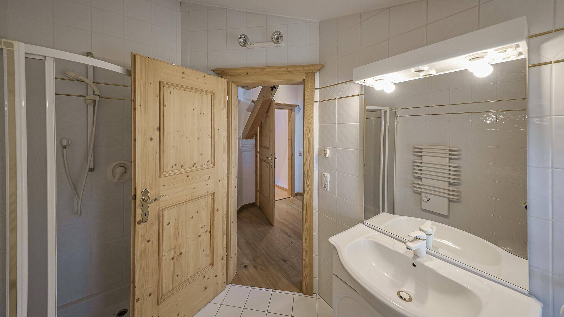 Traditionelles Badezimmer mit Duschkabine, Einzelwaschbecken und Spiegel.