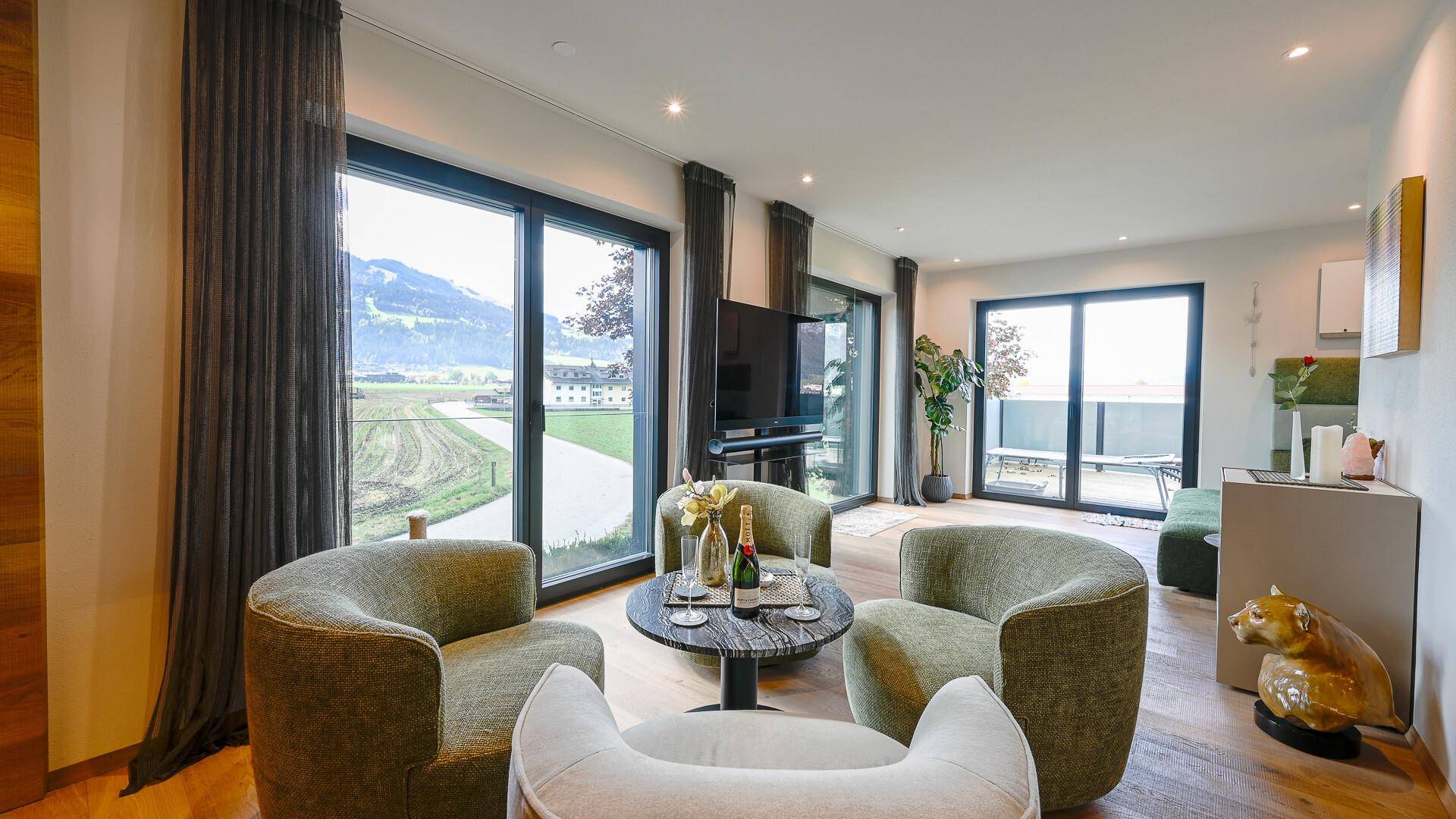 Geräumiges Wohnzimmer mit mehreren Sitzgelegenheiten, Holzboden und Panoramablick auf die Landschaft.