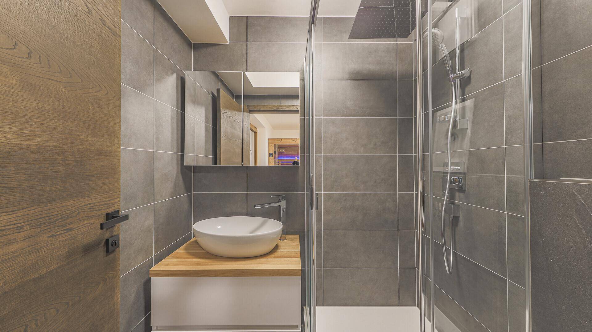 Kleines, modernes Badezimmer mit Dusche, Waschtisch und Spiegelschrank.