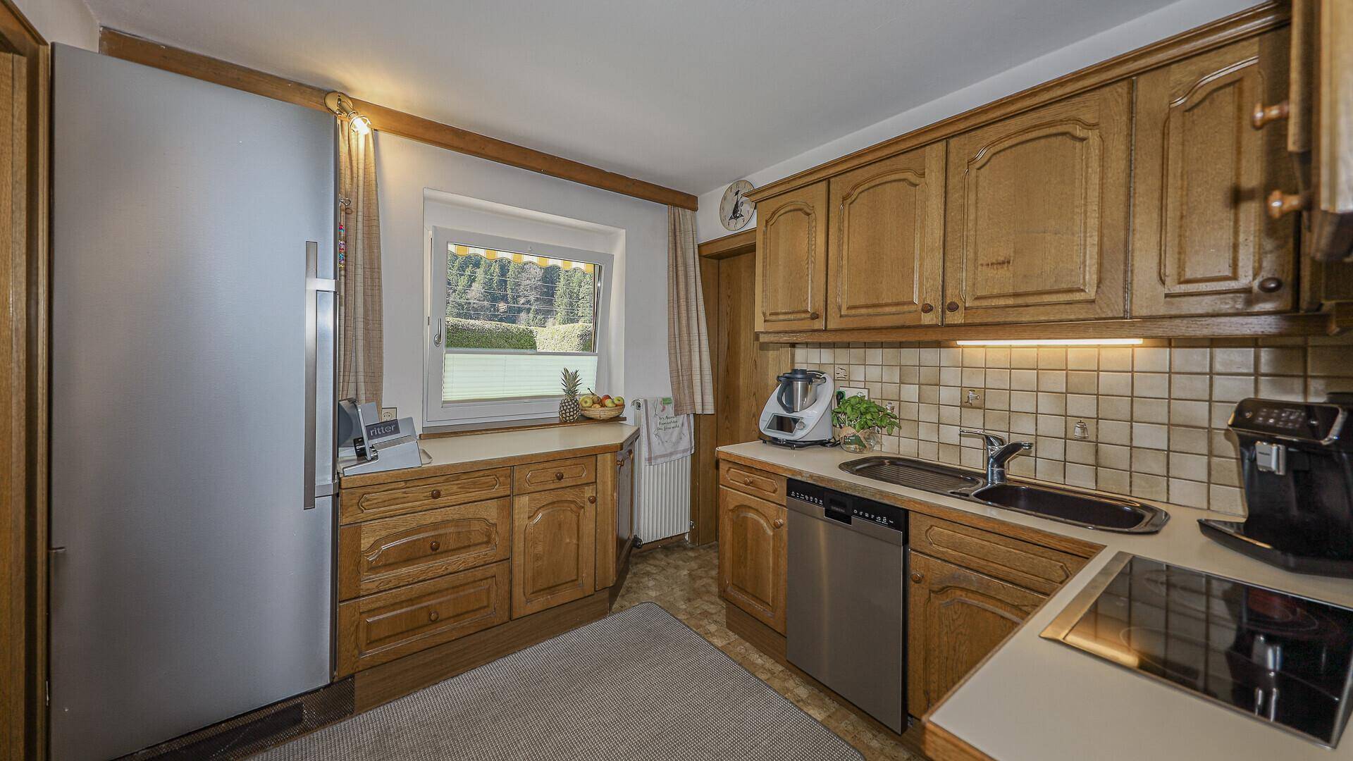 Funktionale Küche im Landhausstil mit Holzschränken, Fliesenrückwand und Fenster.